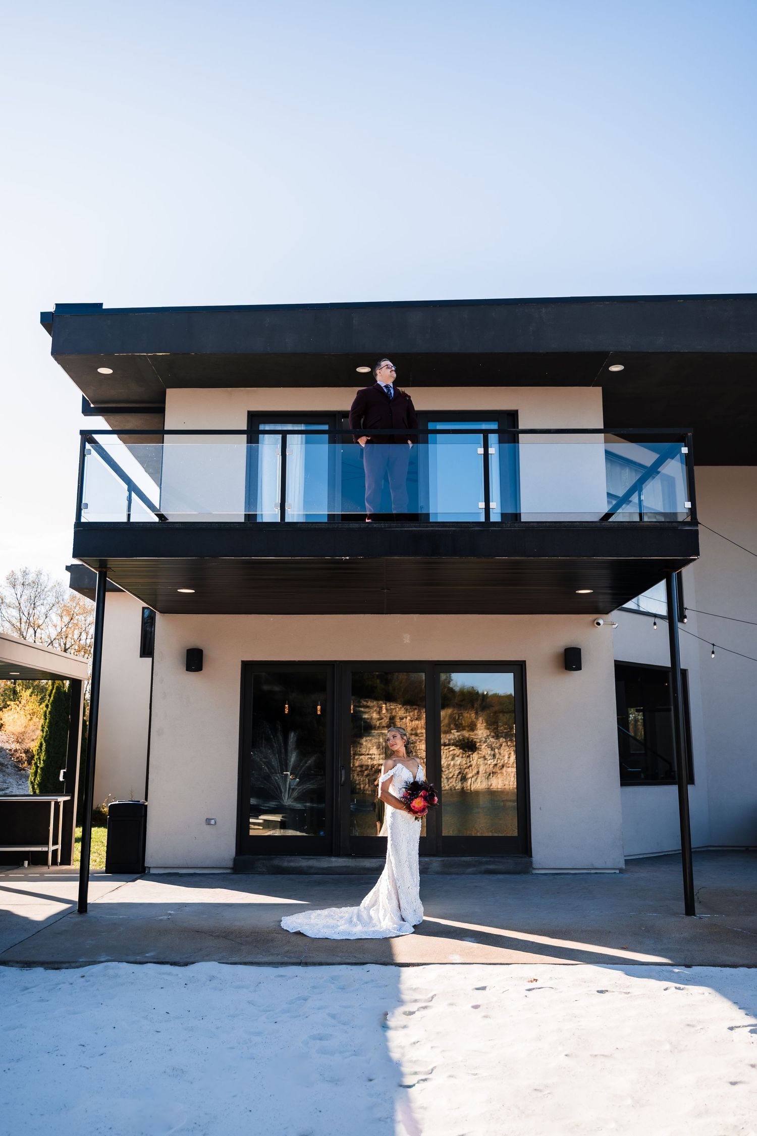 Modern white building exterior with black accents and large windows under sunny skies.