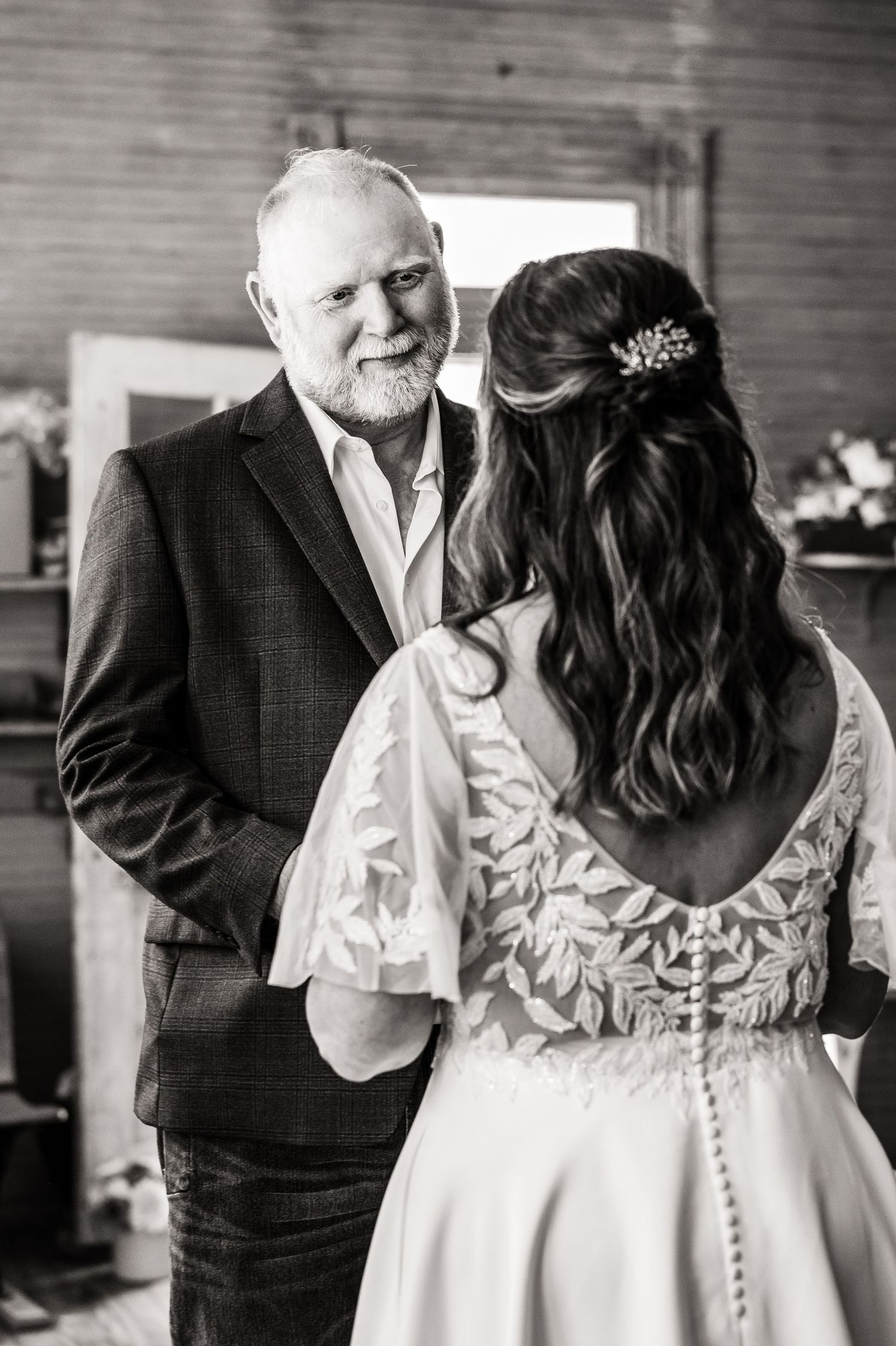 A touching moment during a wedding ceremony in a rustic indoor venue with wooden plank walls.