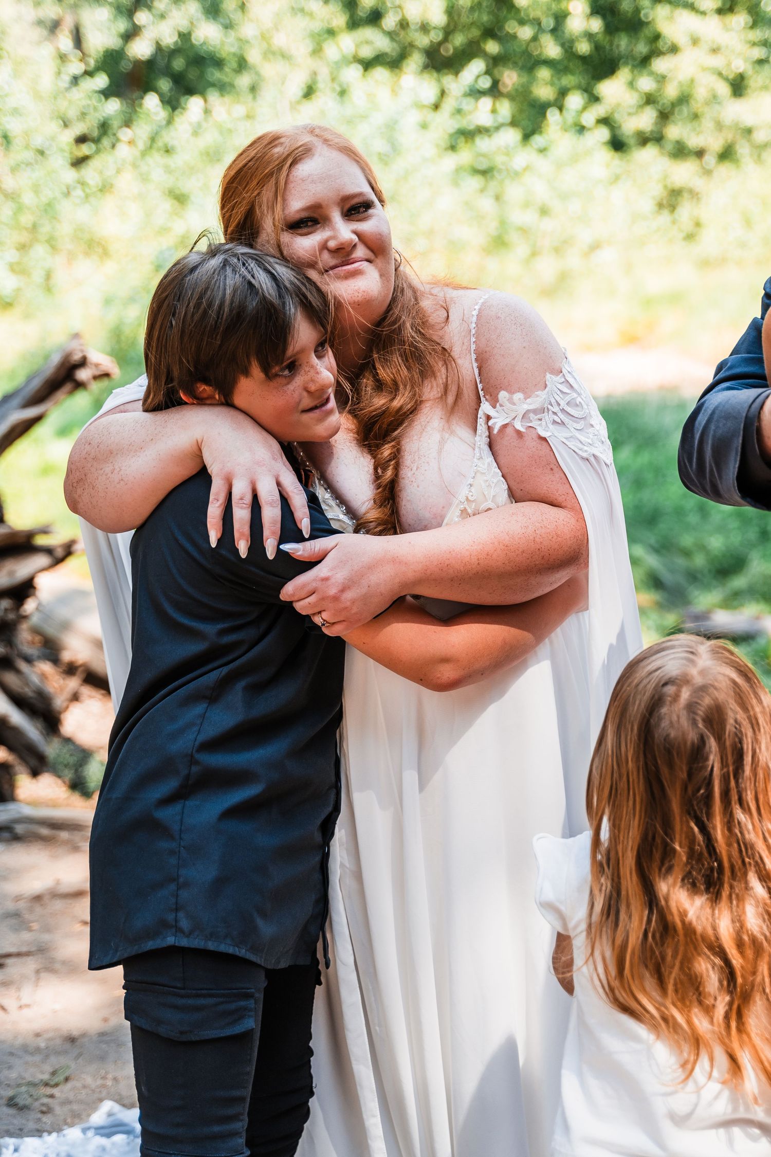 Wedding celebration with intimate embrace between couple against natural outdoor backdrop.
