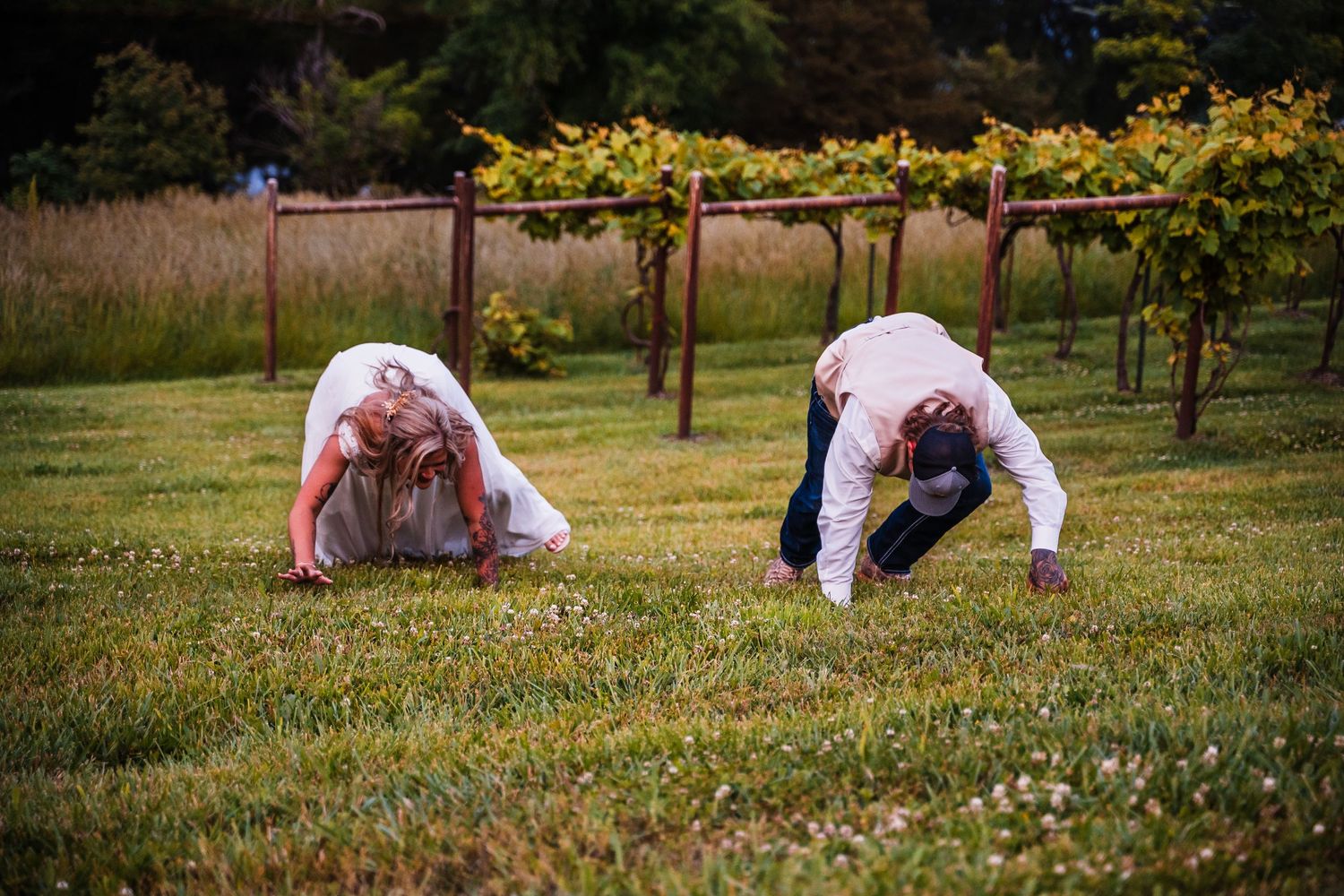 People crouch to pick flowers in a sprawling meadow at sunset.