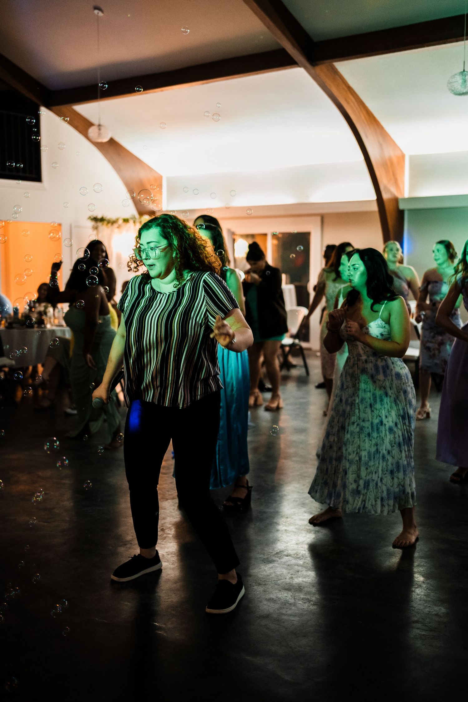 People dancing under colorful party lights at a wedding reception.