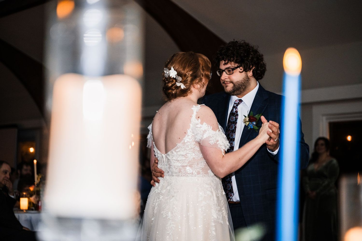 A couple shares their first dance at a candlelit wedding reception with romantic lighting.