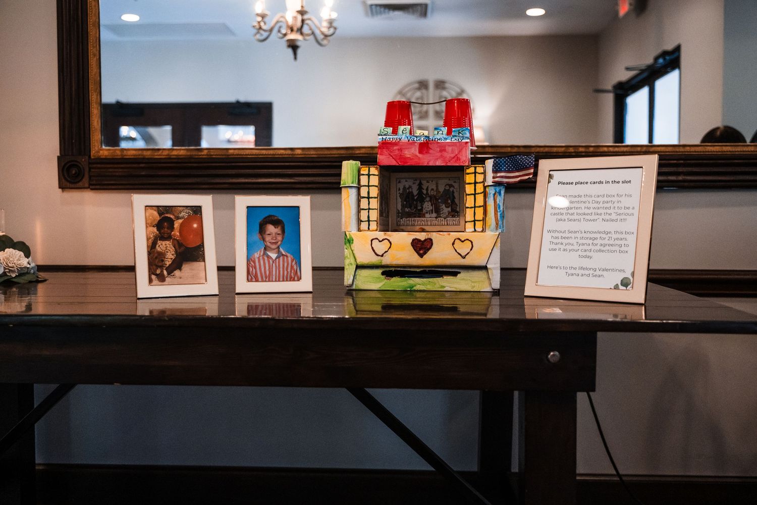 Vintage jukebox centerpiece flanked by framed photos on a dark wood table at a wedding reception.