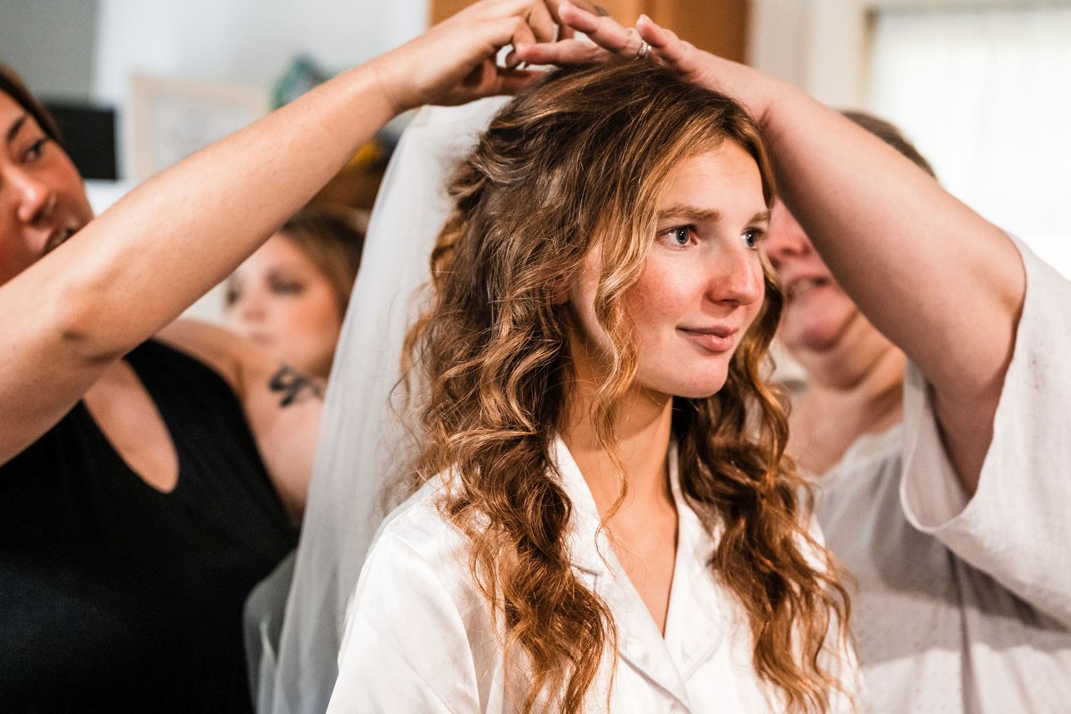 Wedding preparation moment showing final touches being added to bridal hair and veil.