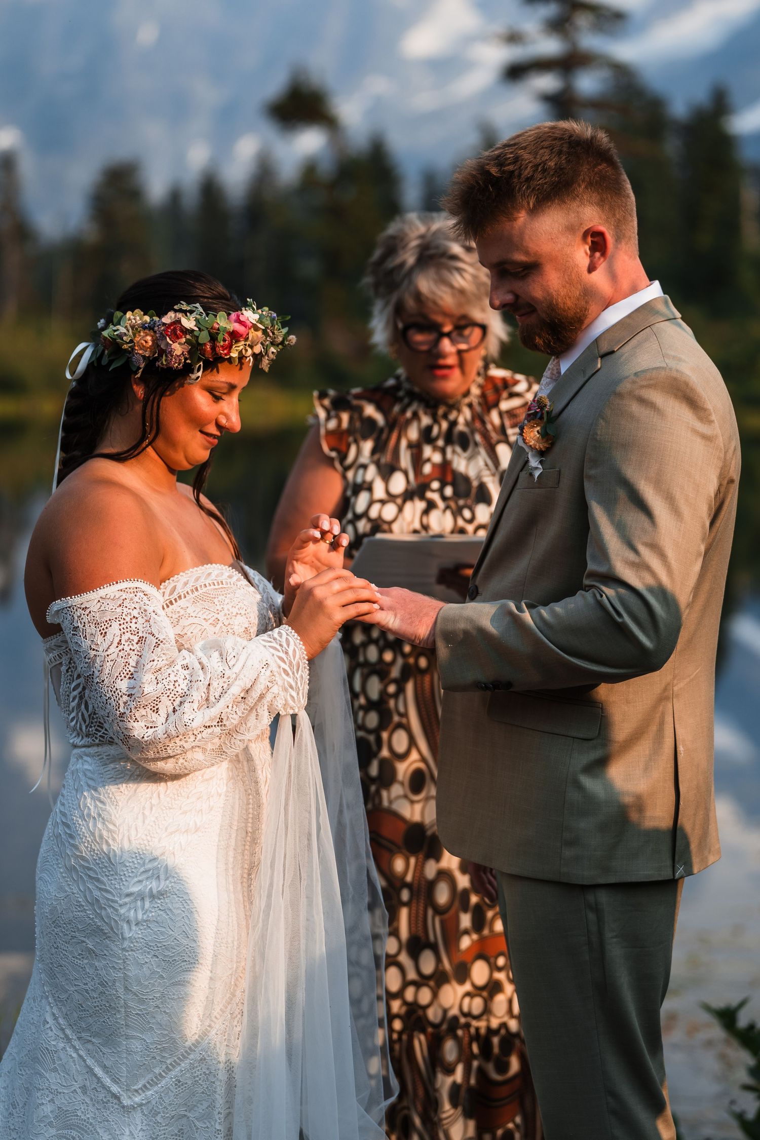 A wedding ceremony takes place against a backdrop of evergreen trees and mountain vistas.