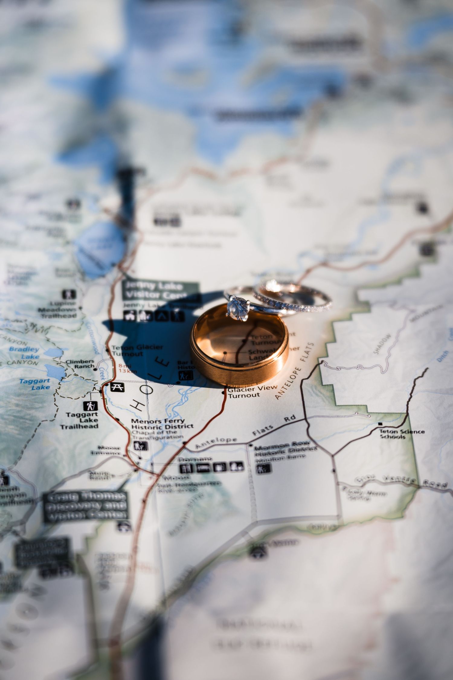 Wedding rings rest on a detailed paper map with routes and locations marked in selective focus.