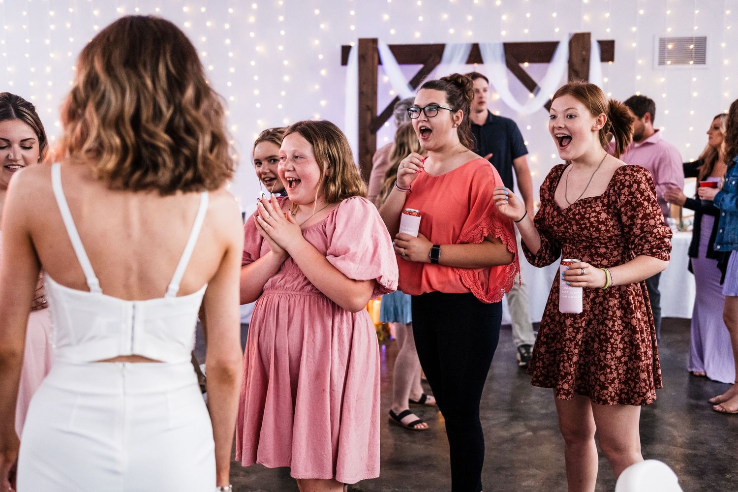 Wedding guests reacting with joy as they watch the bride dancing at reception.