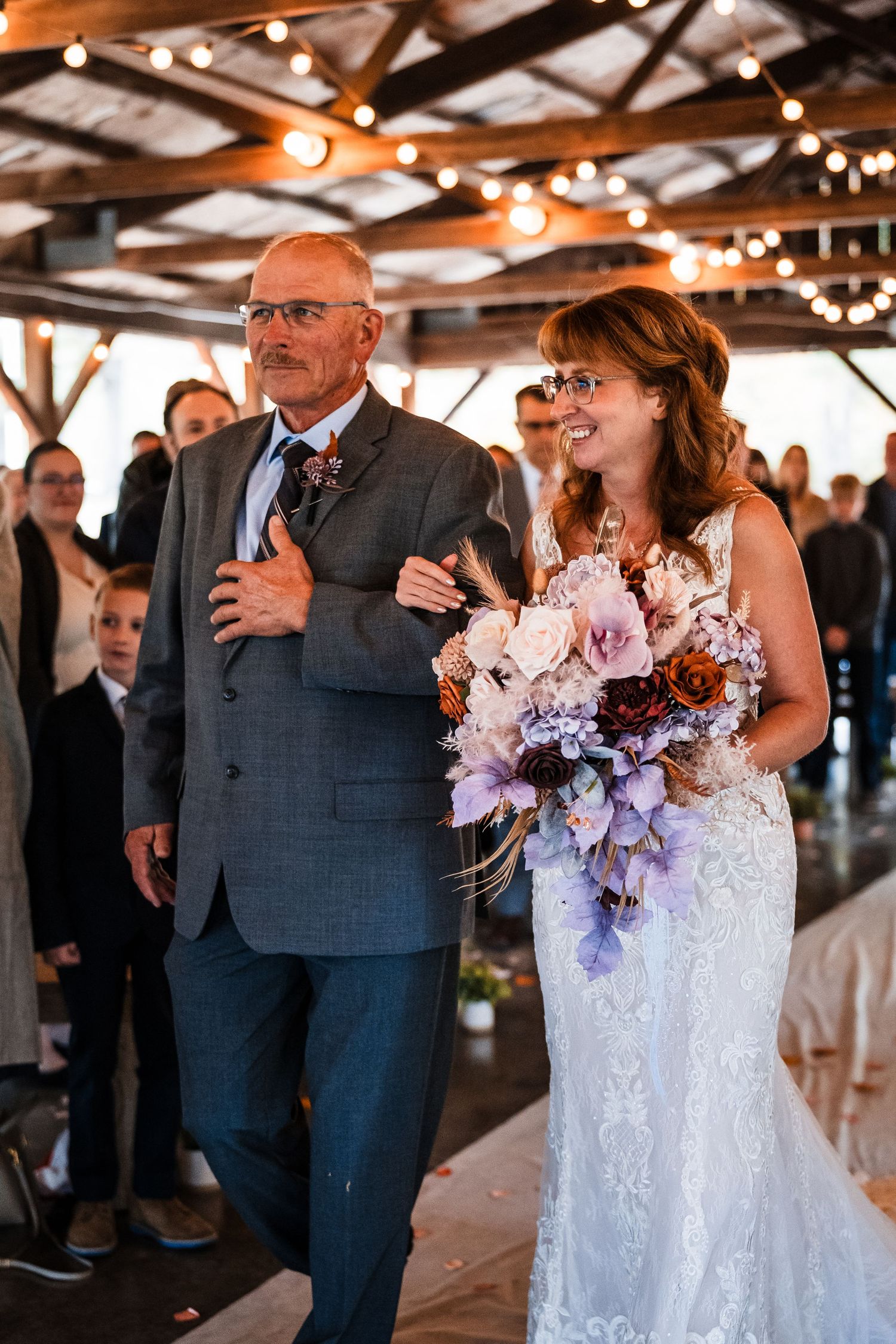 Wedding celebration in a rustic covered pavilion with string lights and elegant decor.