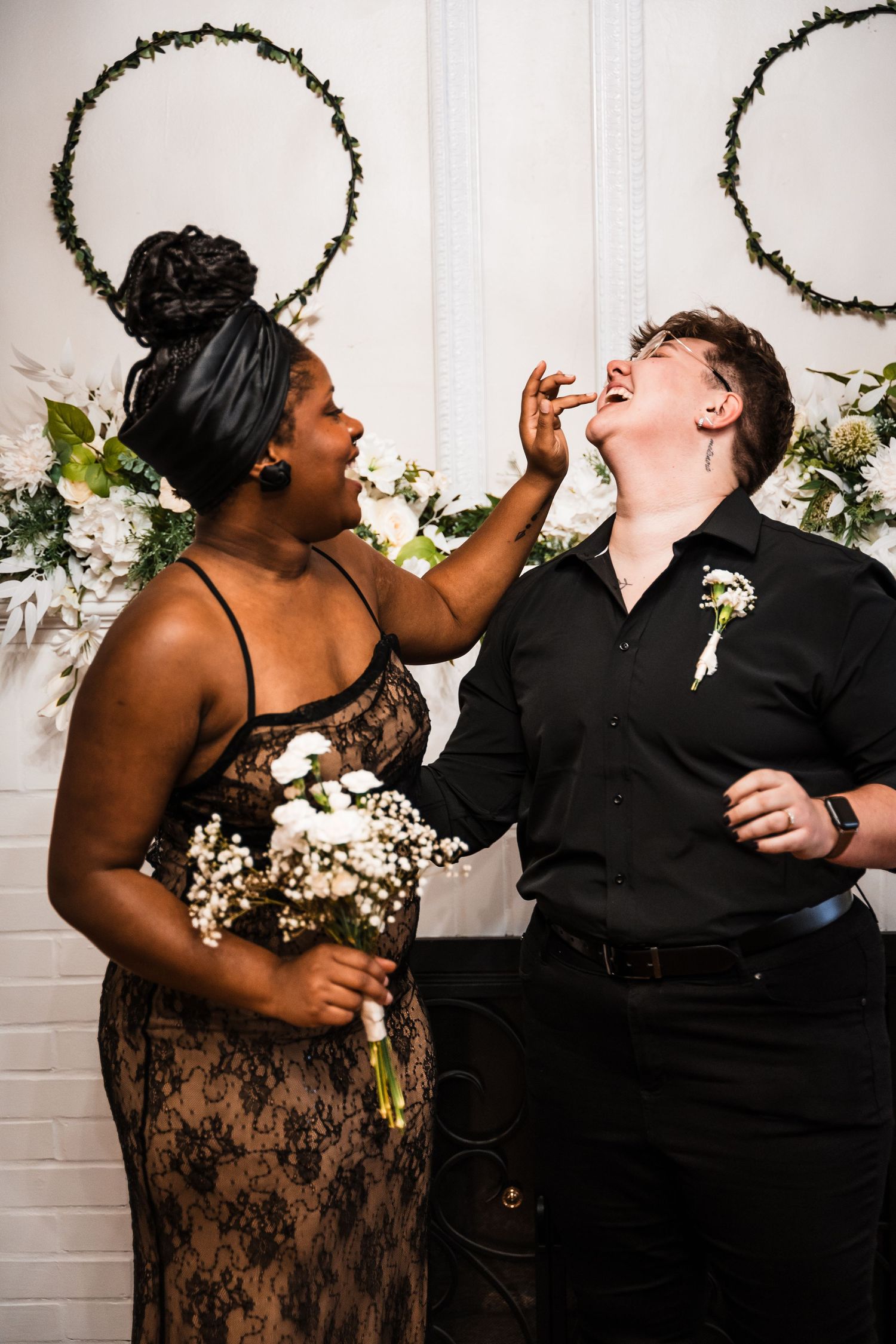 A couple sharing a playful moment during their wedding photoshoot with white floral decorations.