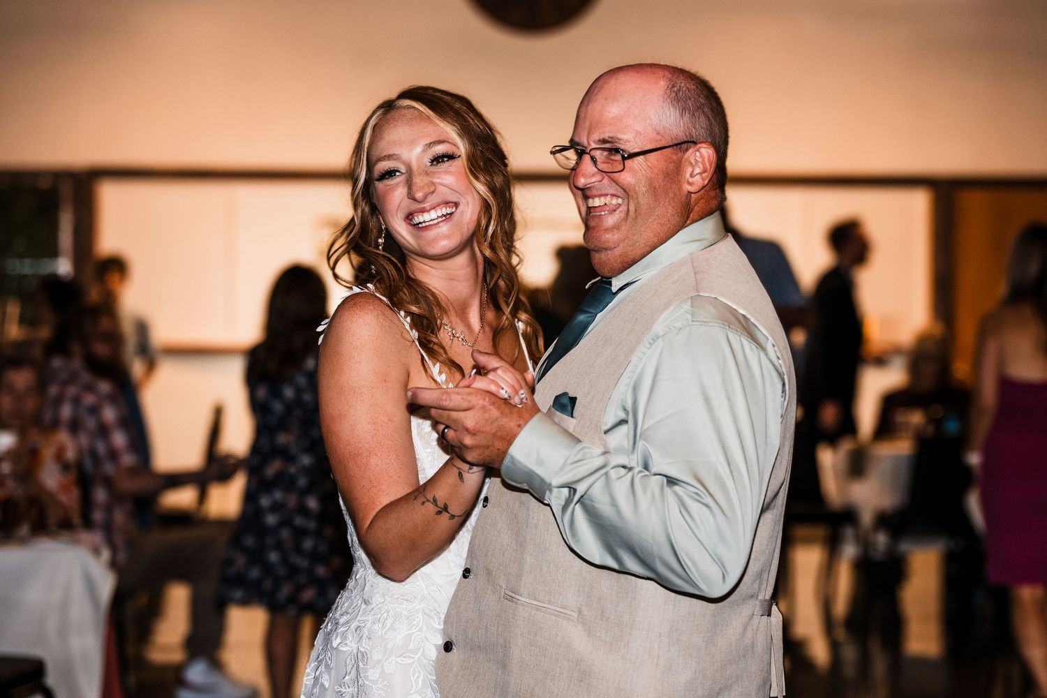 Couple shares joyful dance moments at indoor wedding reception.