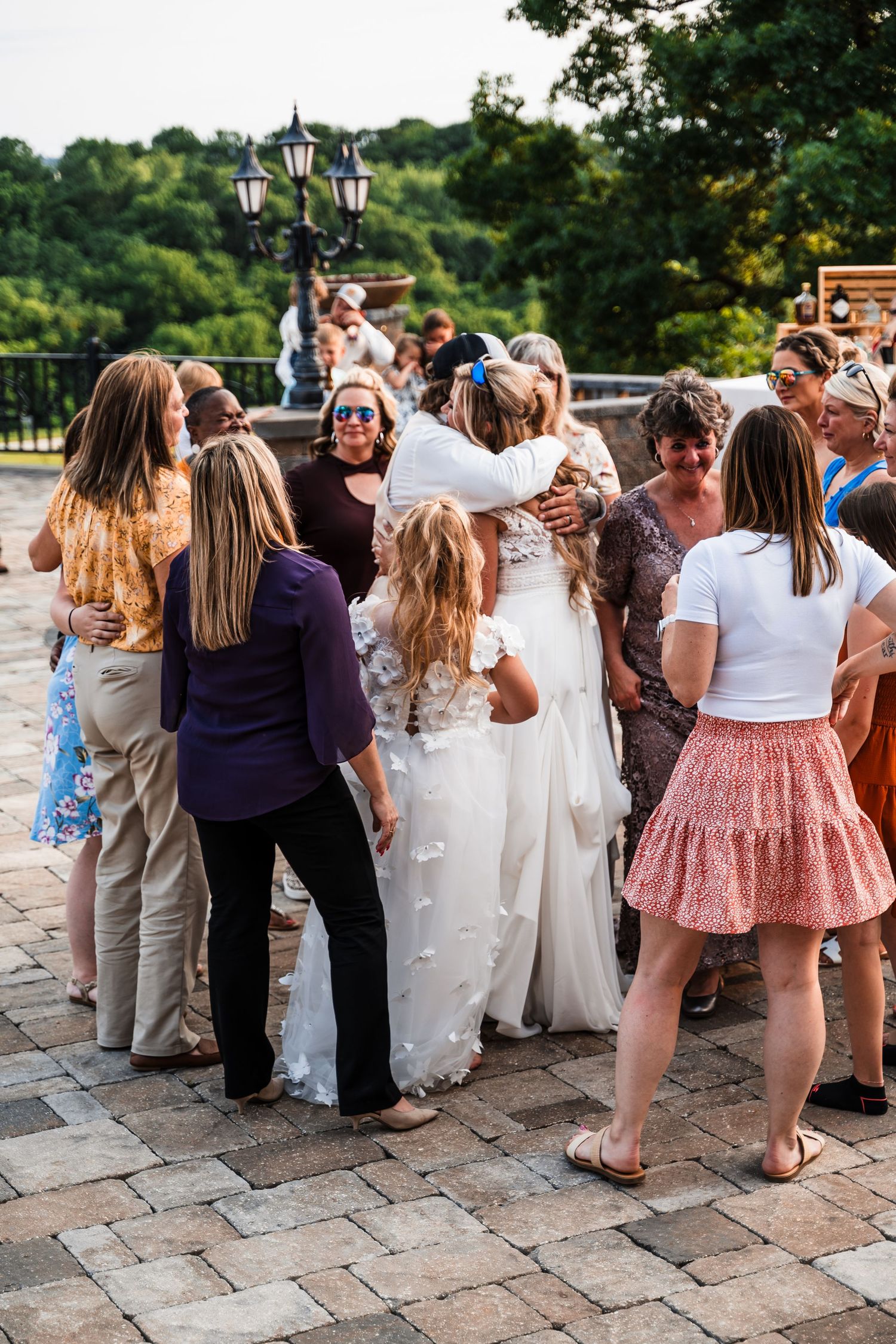 Wedding guests gather in casual attire on a stone patio during an outdoor celebration.