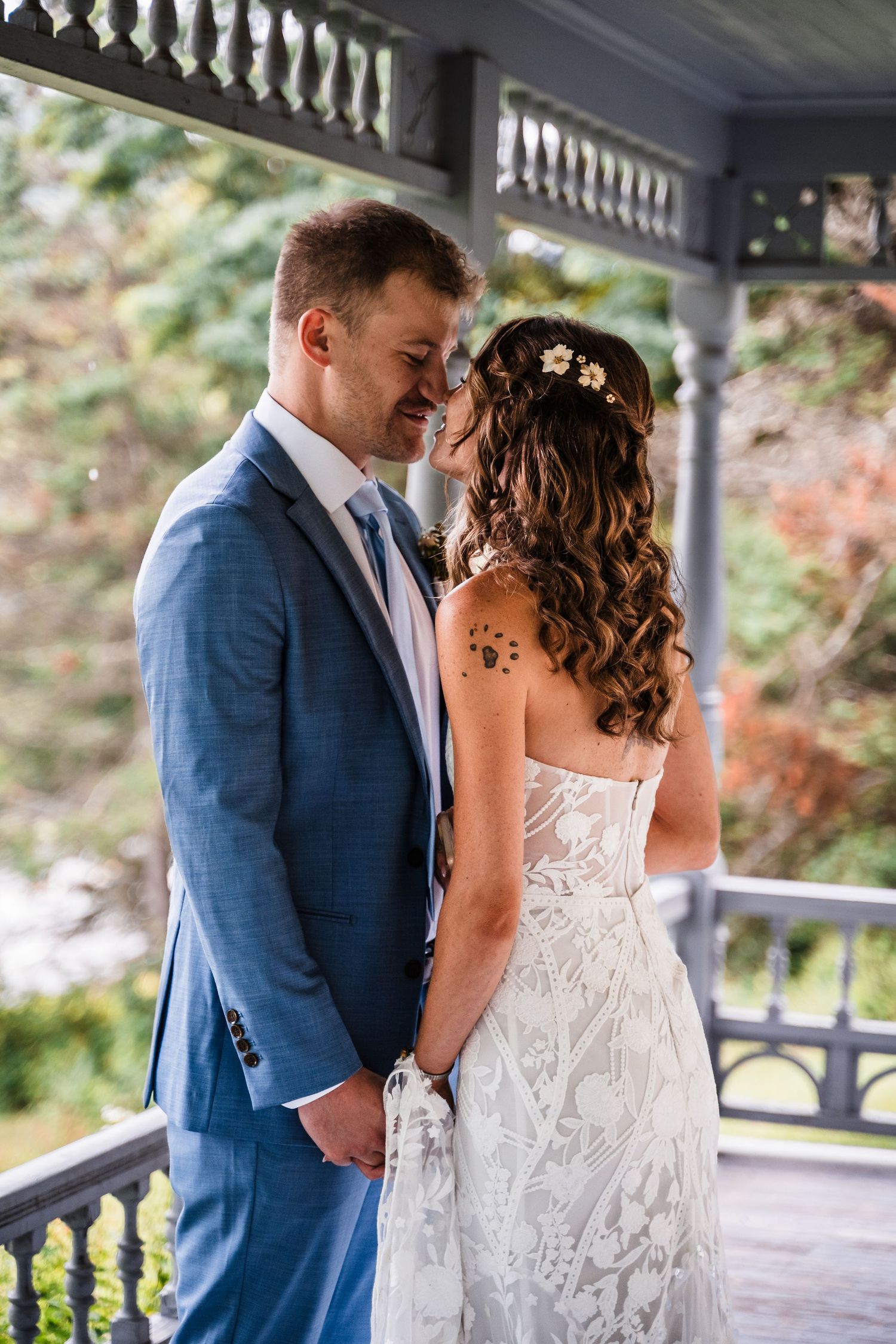 Wedding couple sharing intimate moment on vintage porch with decorated railings.