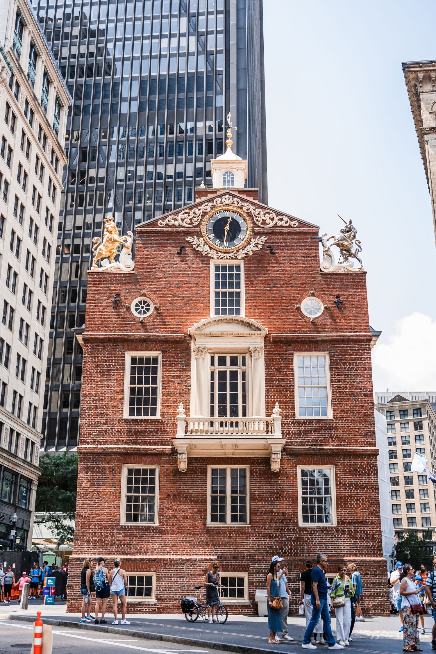 Historic Old State House building with red brick facade and colonial architecture stands among modern skyscrapers in Boston.