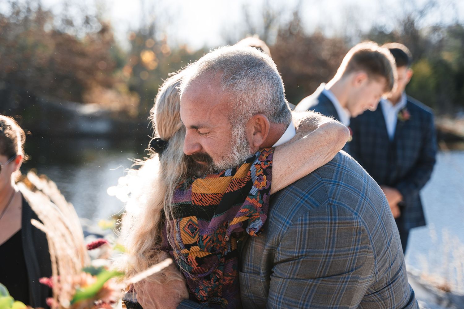 Close-up candid moment during outdoor gathering showing person in plaid jacket and patterned scarf.
