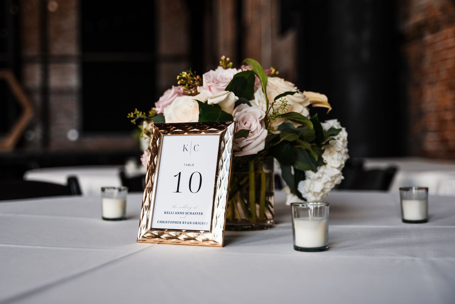 Wedding reception table decor featuring table number 10 with floral centerpiece and votive candles.