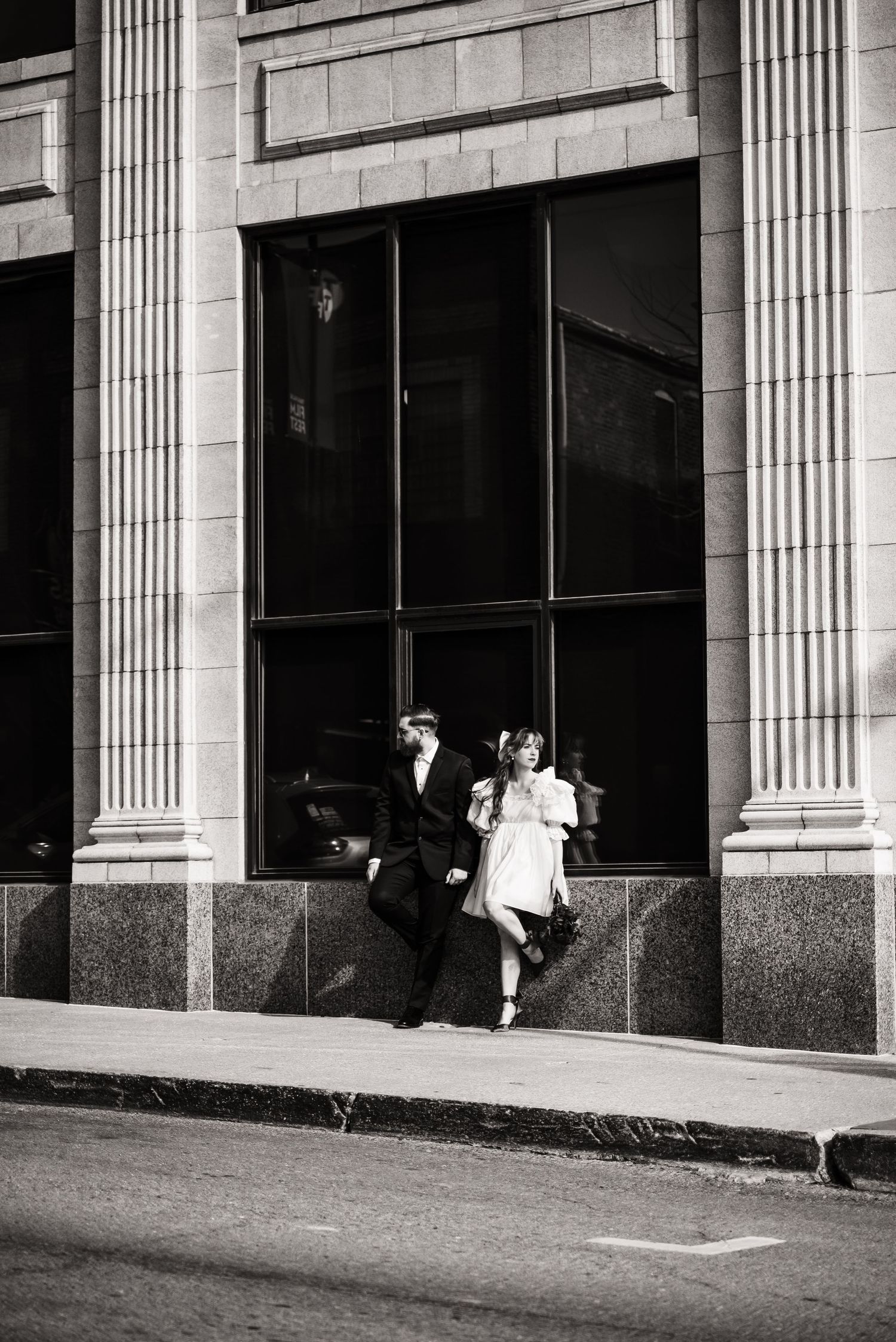 Black and white photo of couple posing between classical columns of historic building.