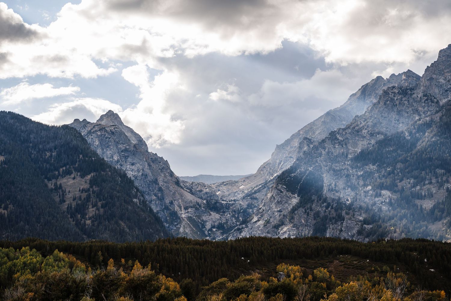 Panoramic view of jagged mountain peaks under dramatic cloudy skies.