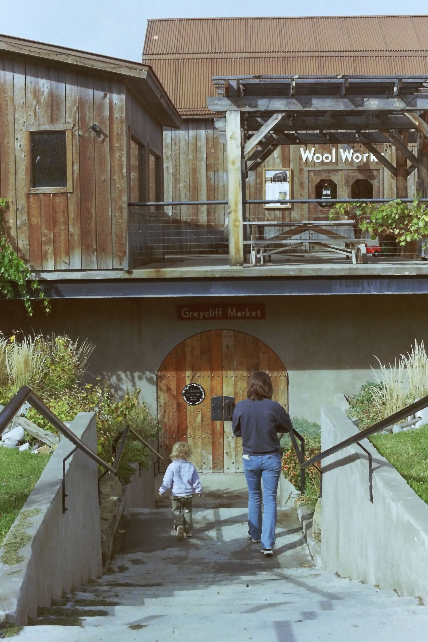A sequence of images showing someone walking up concrete steps outside a wooden building with a modern design.