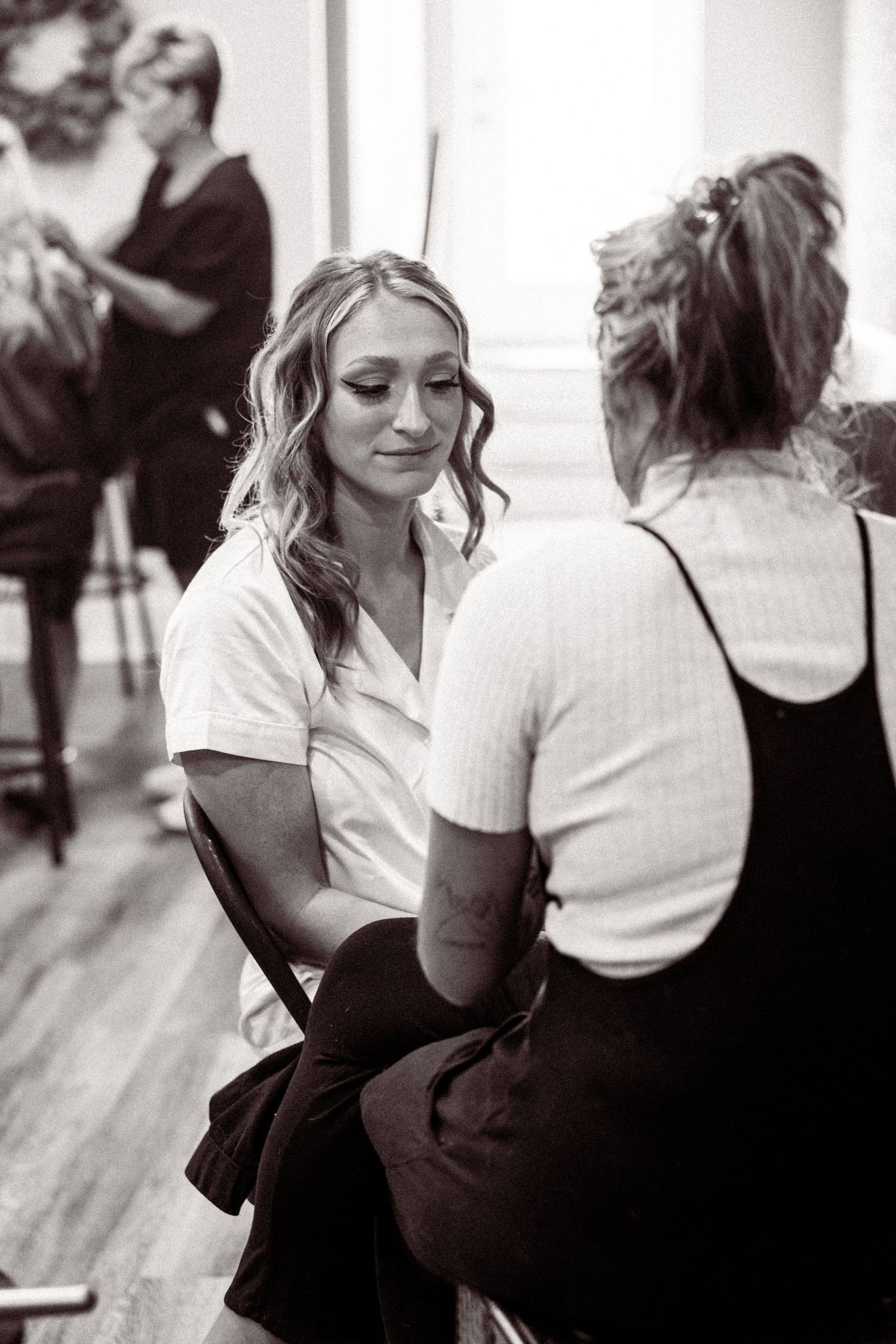 Black and white candid photo of people getting ready in a dance studio with soft natural lighting.