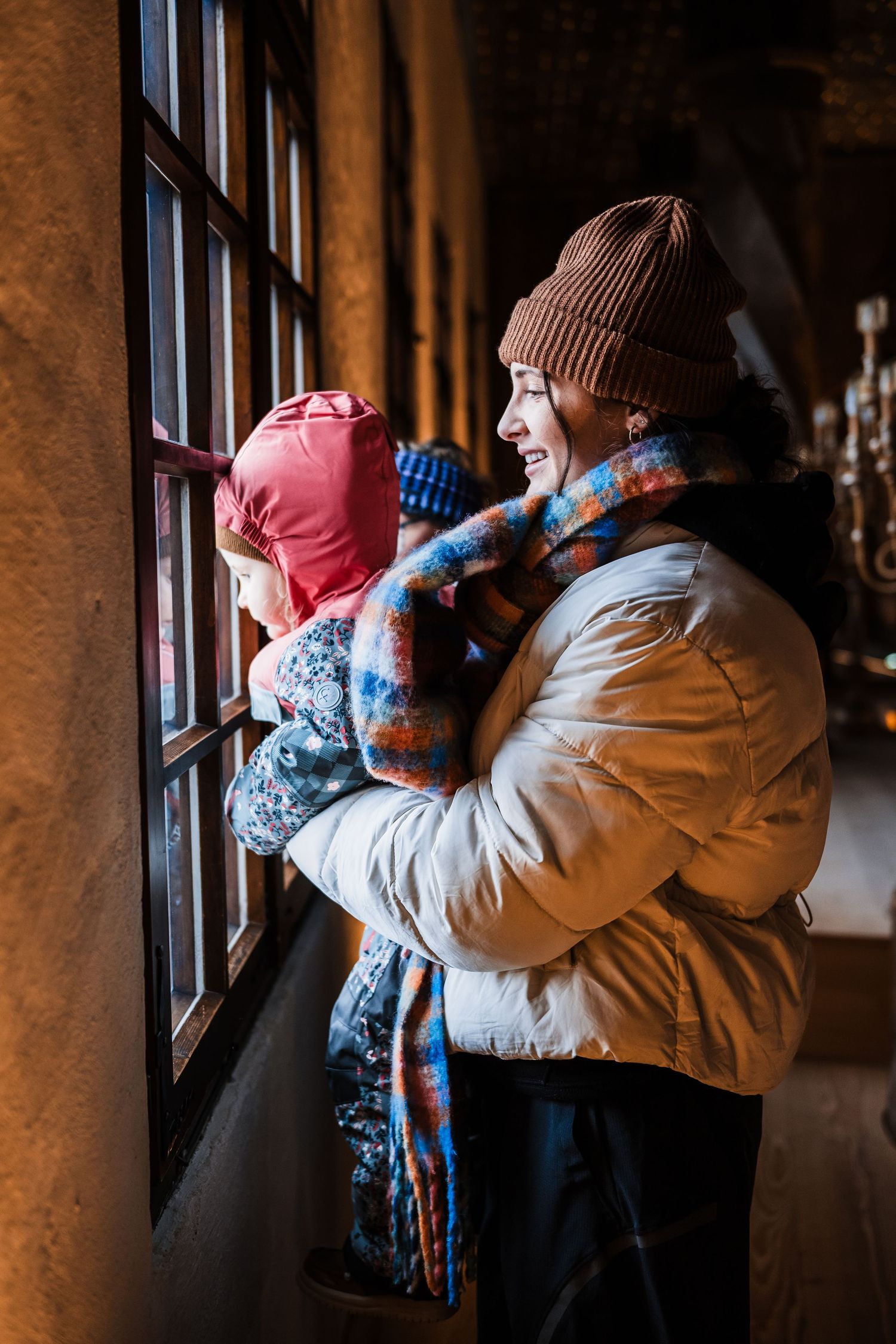 People looking out through windows of a historic building on a winter day.