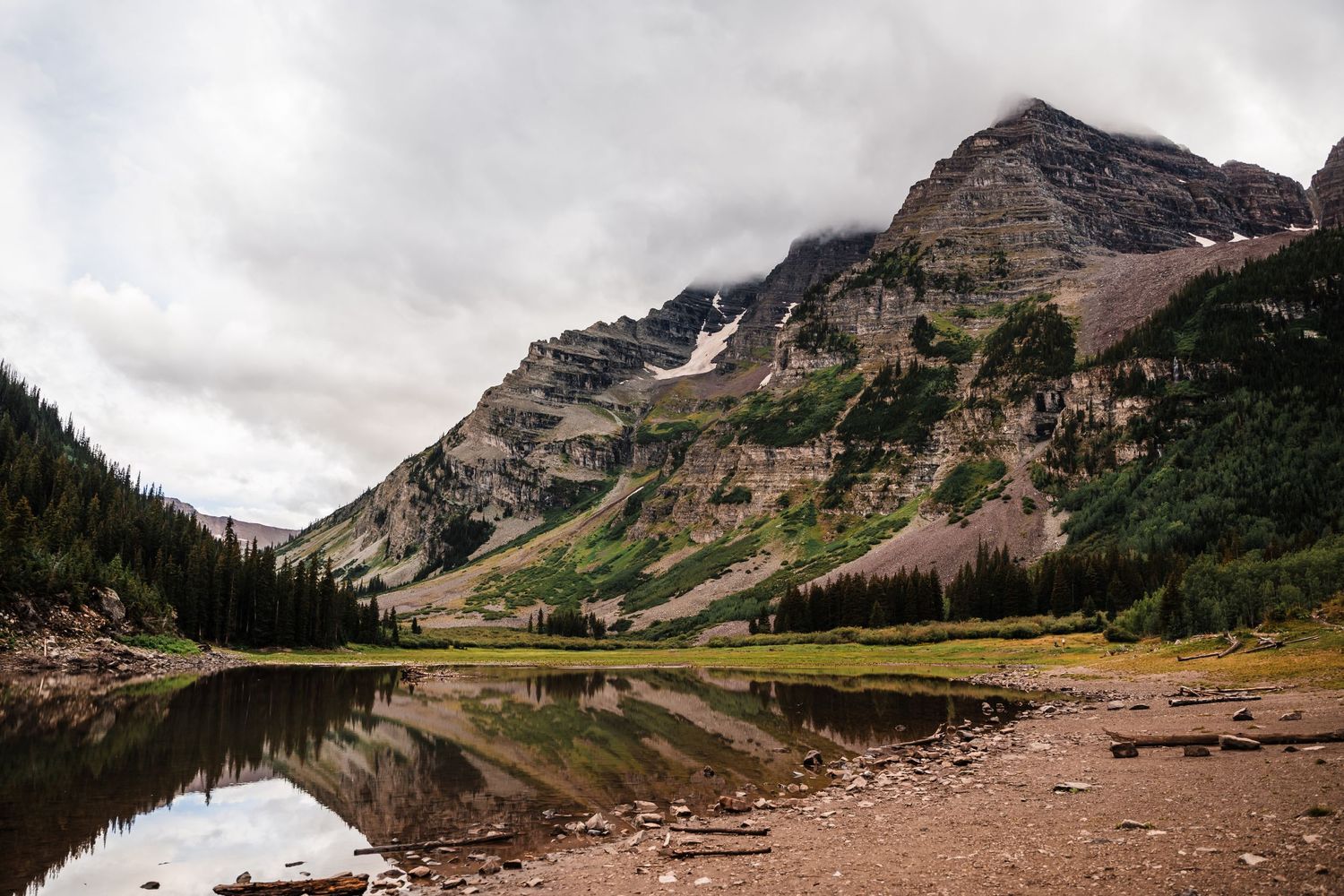Majestic mountain peaks reflecting in a calm alpine lake surrounded by rugged terrain.