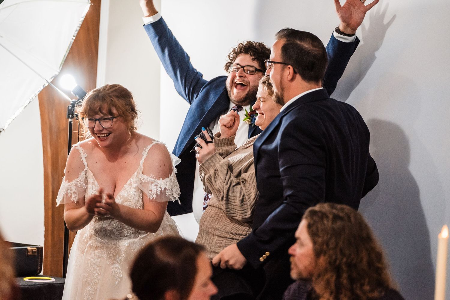 Wedding party celebrates joyfully with raised arms and excited expressions.