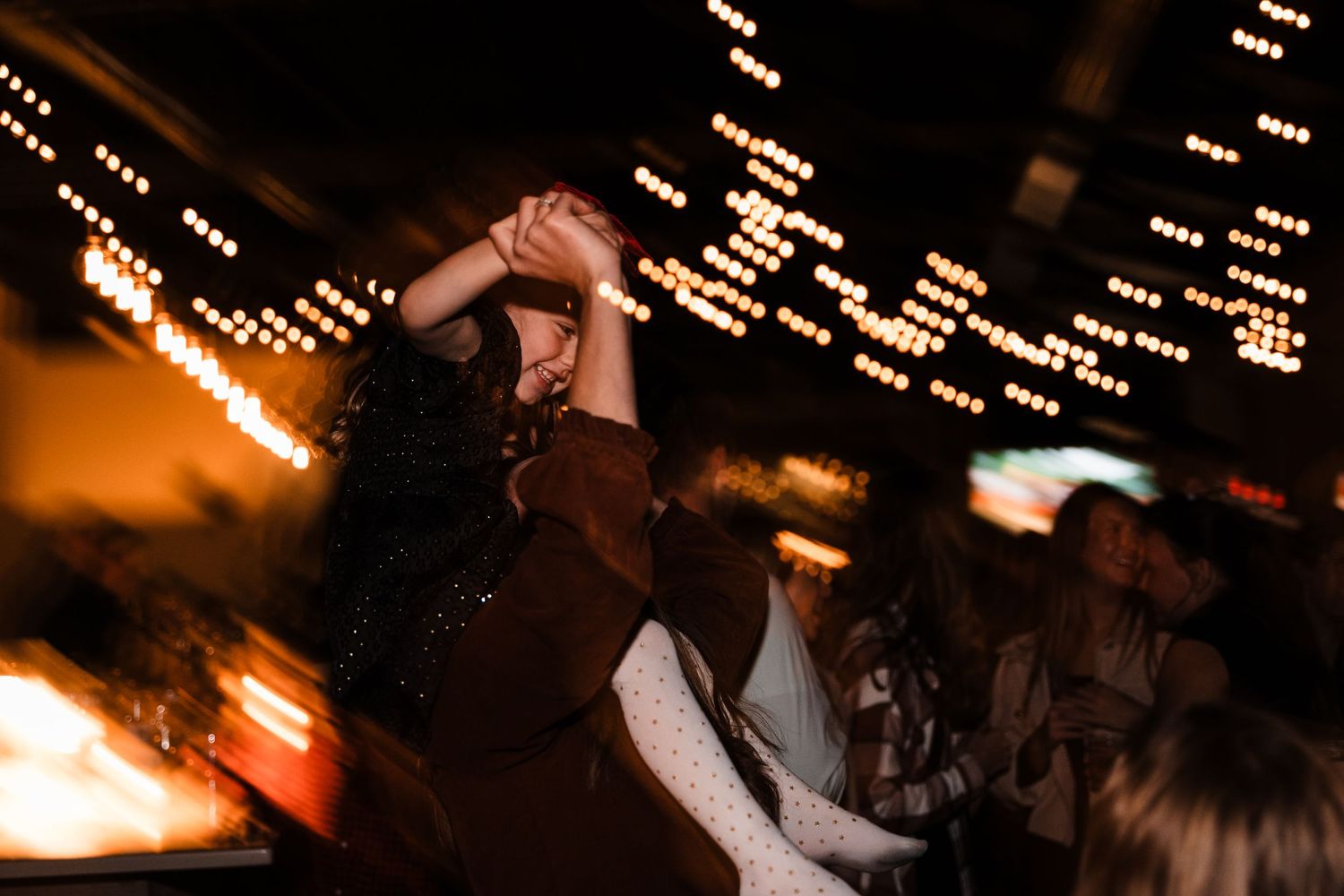 Dancing silhouettes against a backdrop of string lights creating a magical celebration atmosphere.