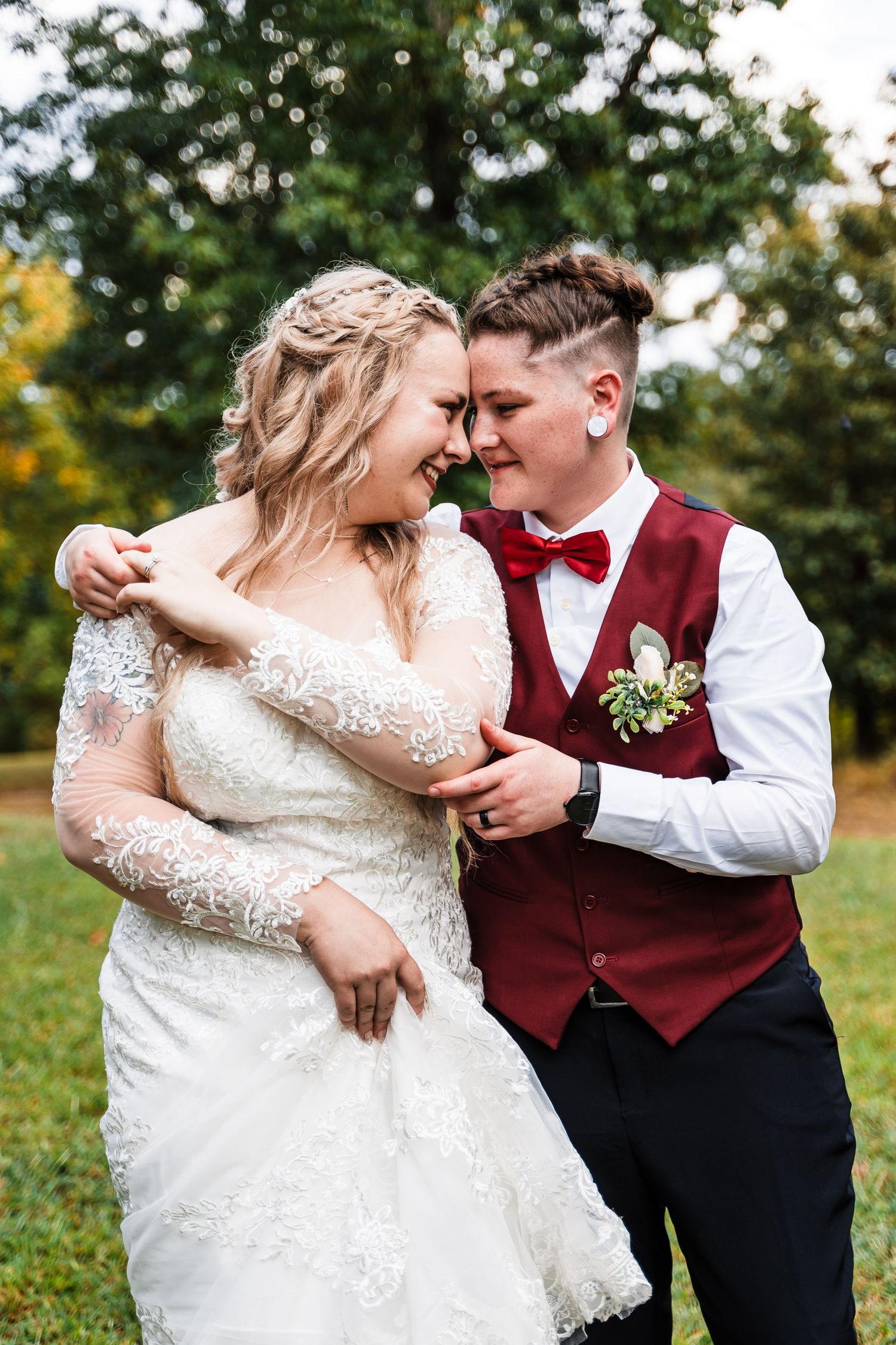 Couple in wedding attire sharing an intimate moment outdoors in a garden setting.