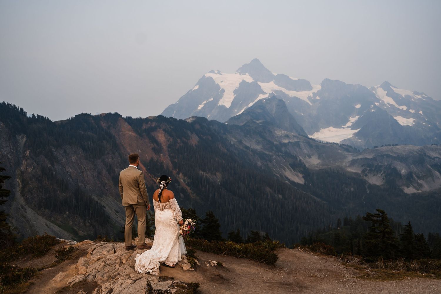 Dramatic mountain landscape with snow-capped peaks under cloudy skies creates a stunning wedding backdrop.