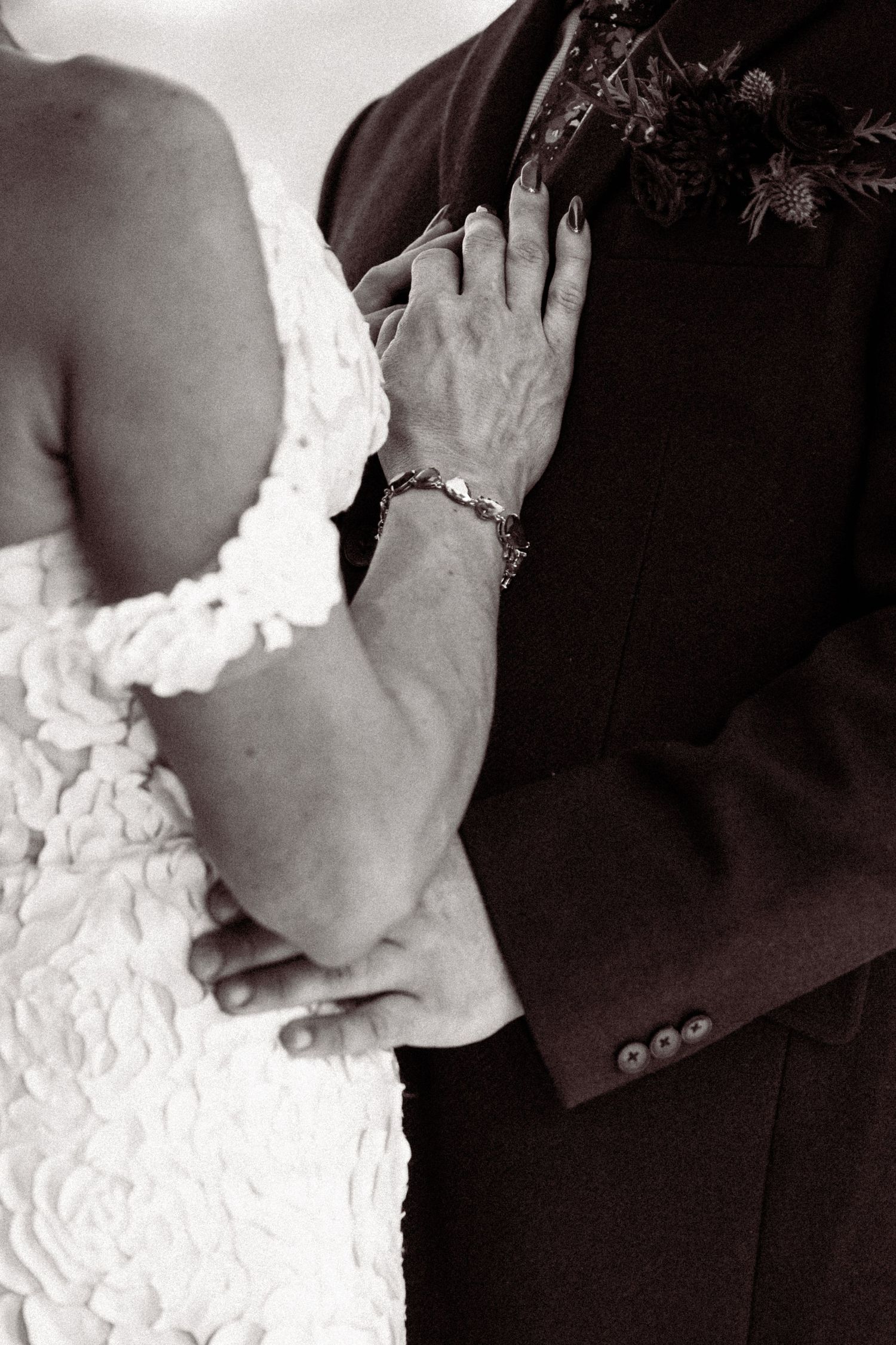 Close-up black and white detail shots of a bride's white lace dress and formal attire.
