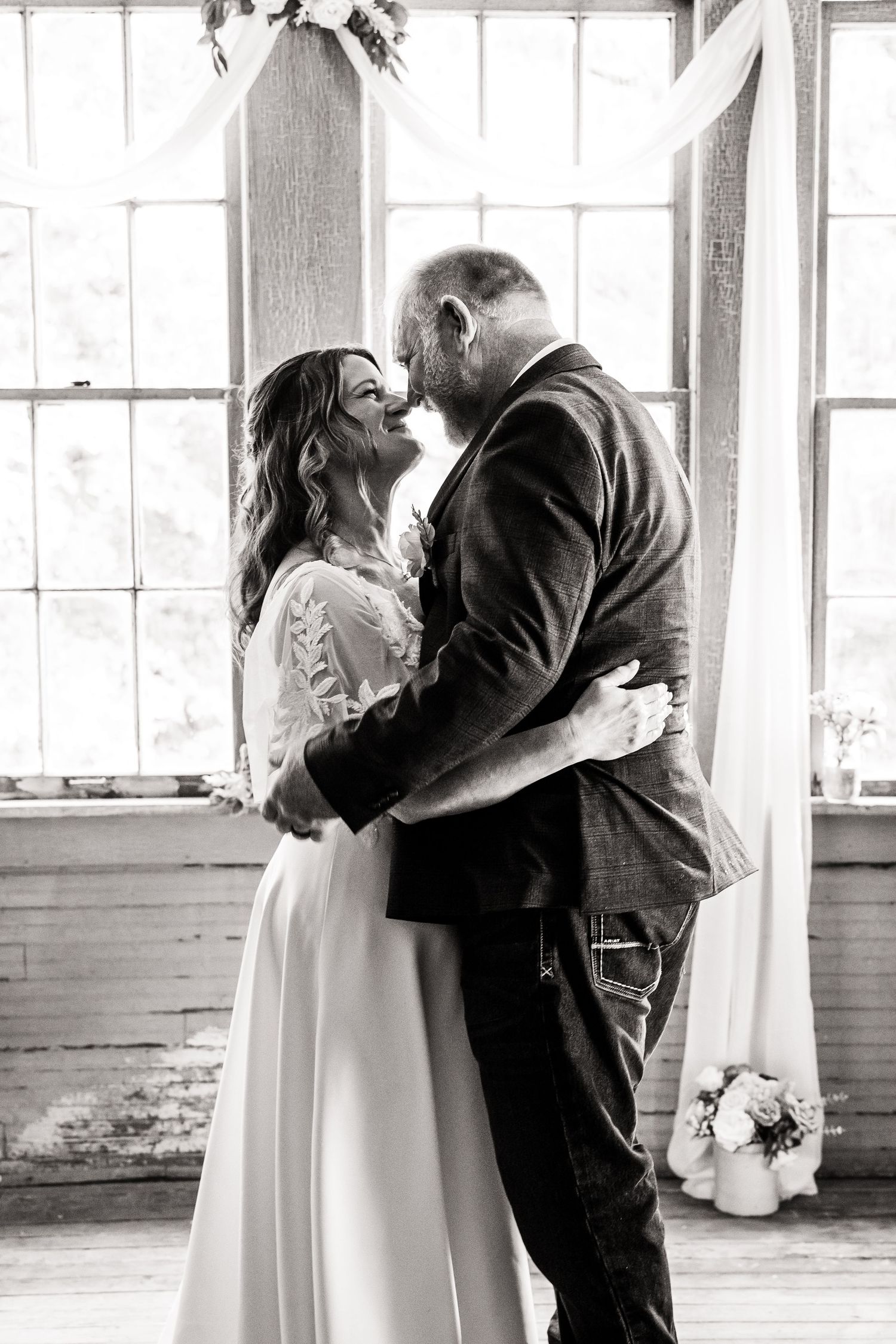 A tender first dance moment between newlyweds in a bright white industrial wedding venue.
