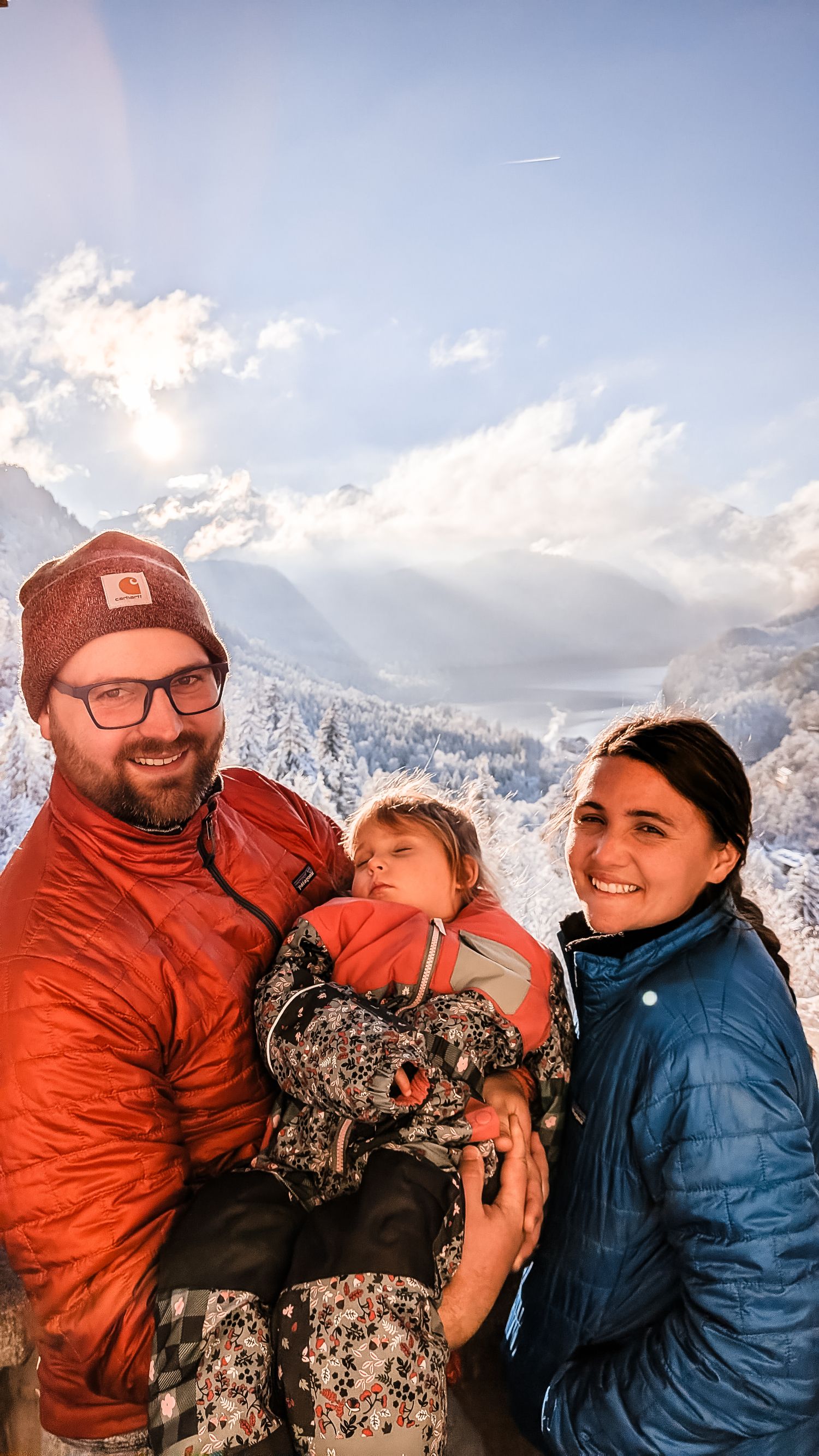 Group enjoying a winter mountain sunset wearing warm outdoor gear in orange and blue colors.