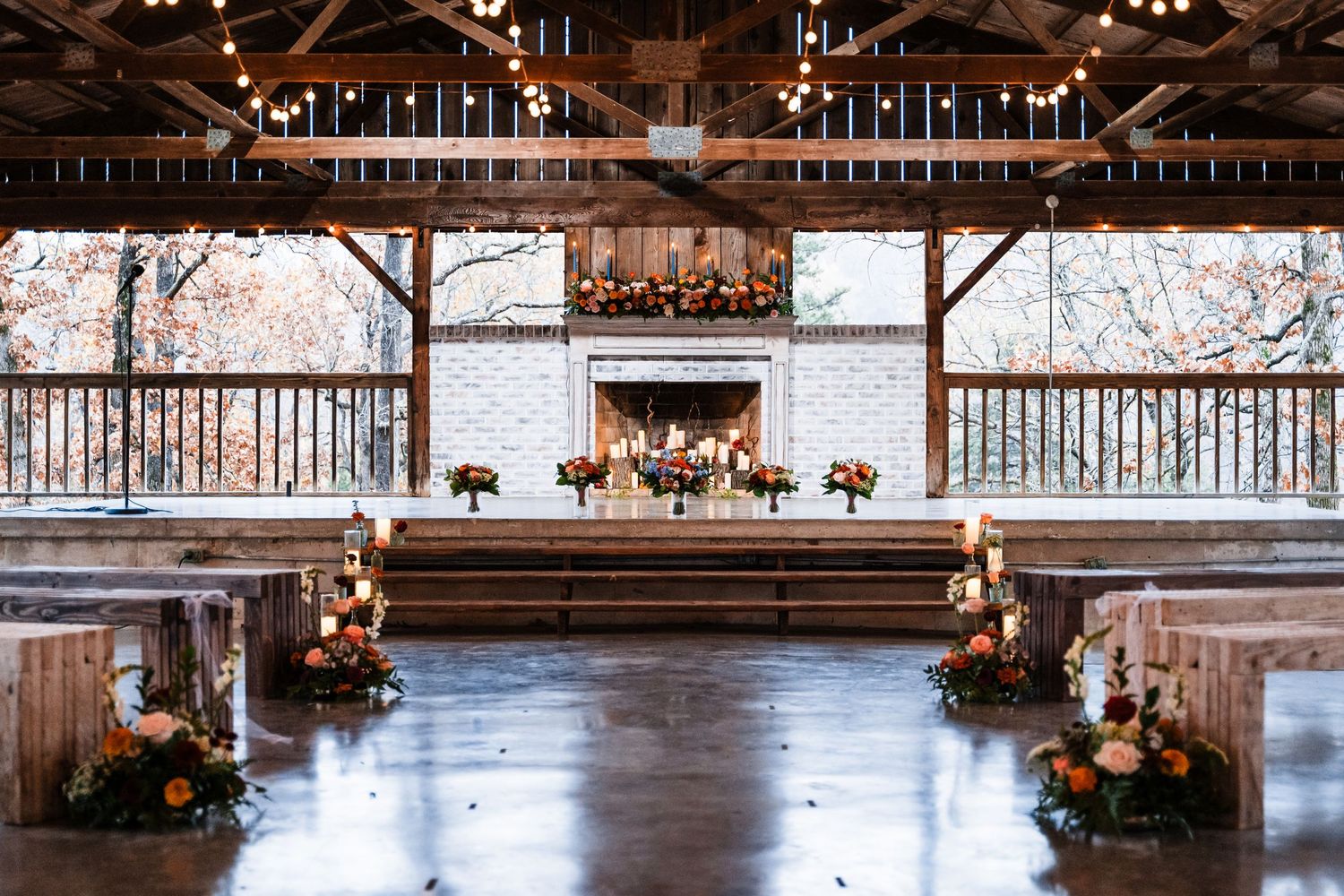Rustic barn wedding venue interior with exposed beams and floral decorations.