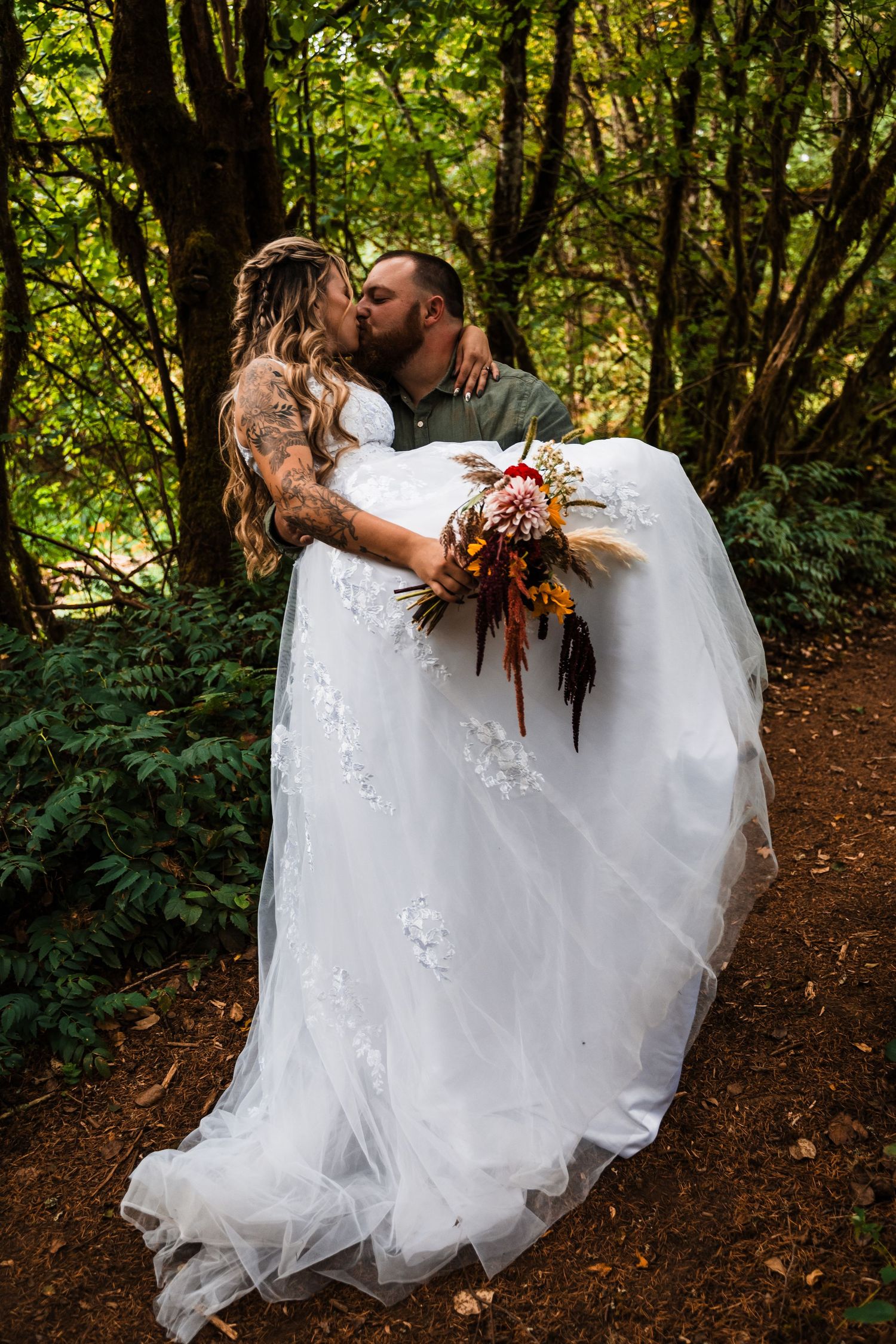 Romantic forest wedding photo with couple embracing among green trees.