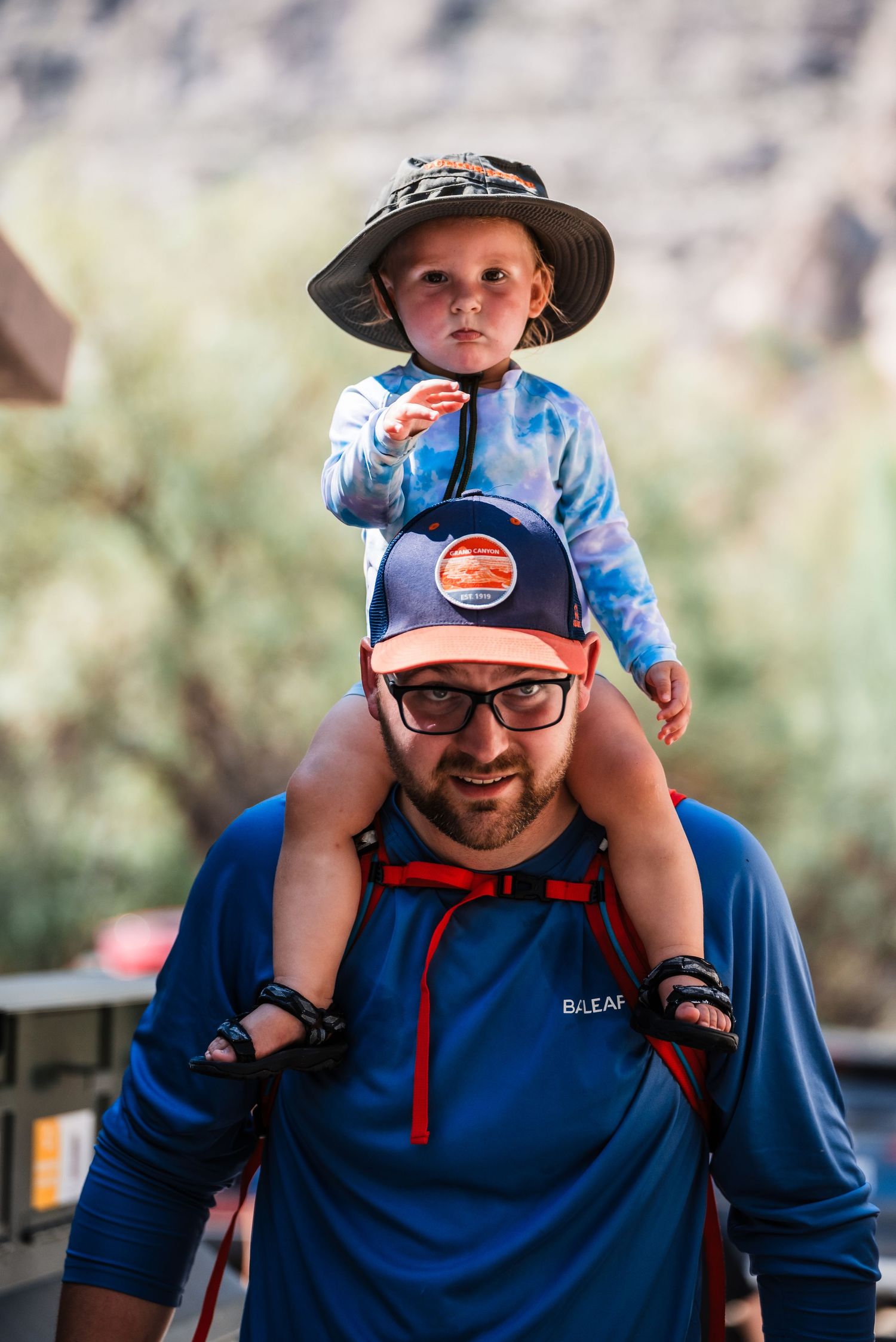 A parent and child enjoying an outdoor adventure wearing sun protection gear in a desert setting.