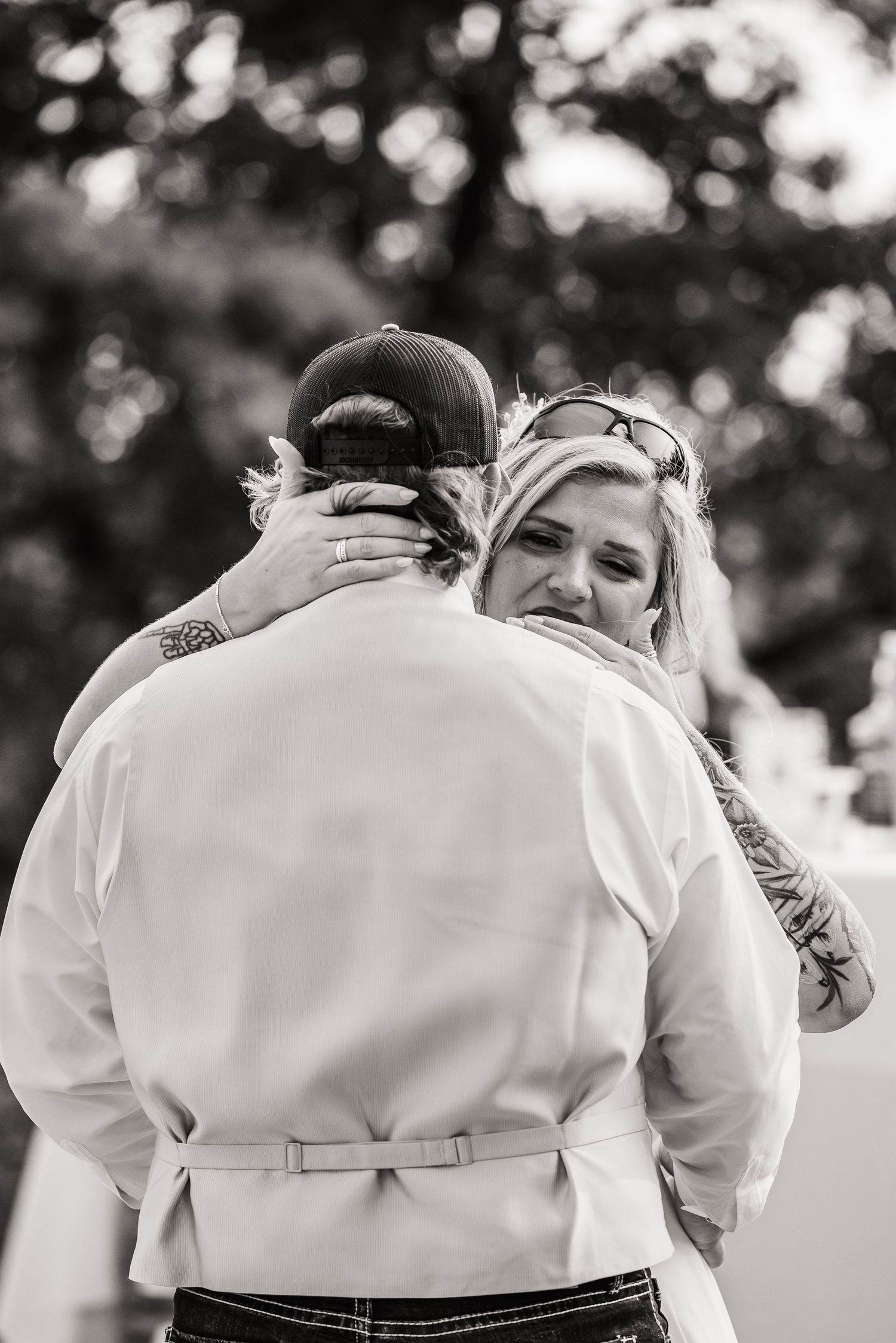 Black and white photo showing intimate wedding party embraces from behind.