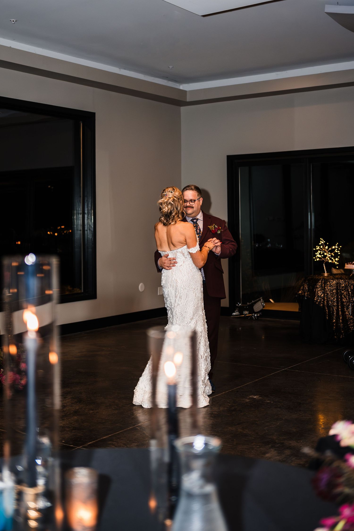 Wedding reception venue with candlelit tables and couples dancing in white dresses.