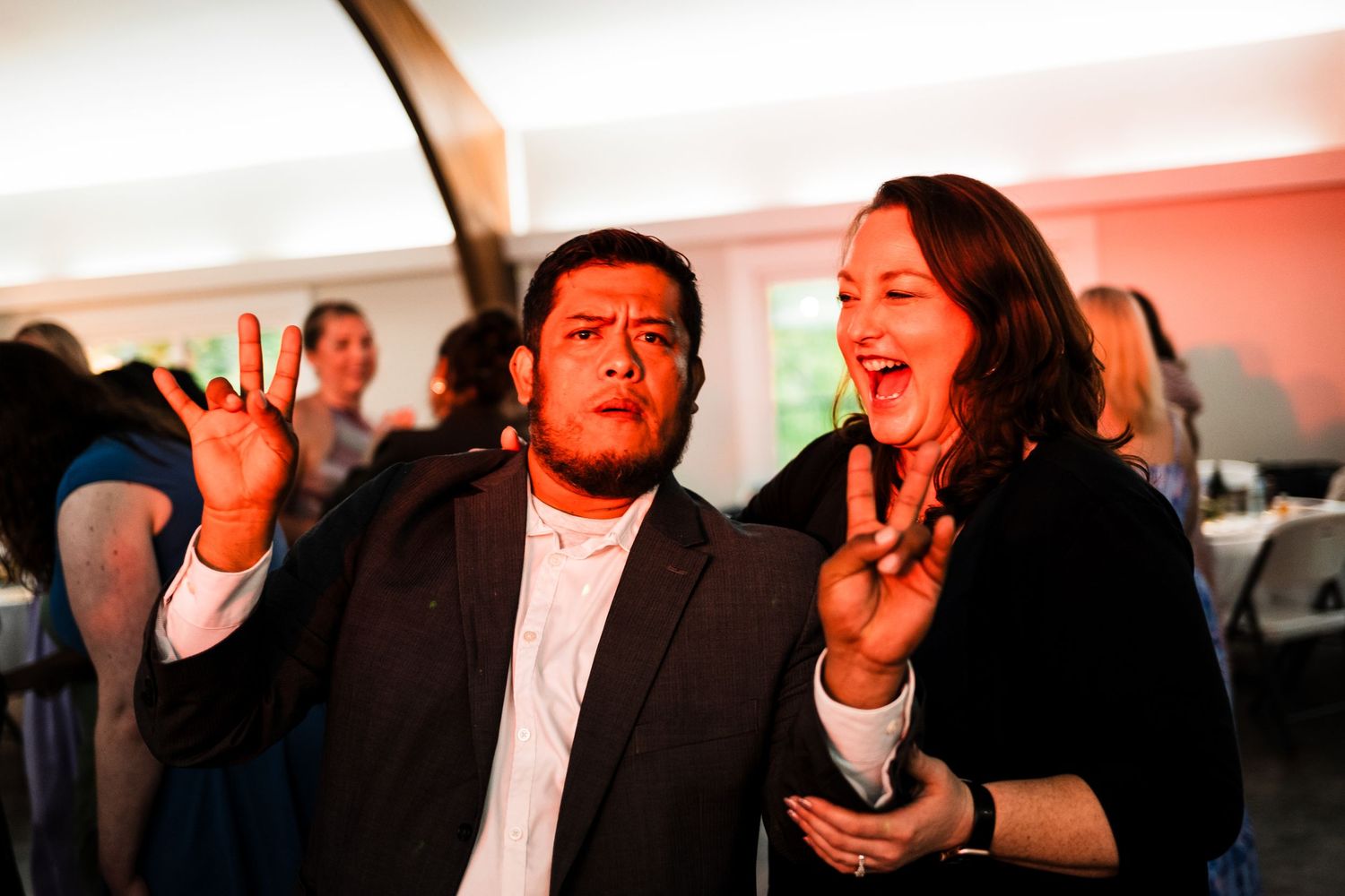 Two guests dancing and singing enthusiastically at a wedding reception celebration.