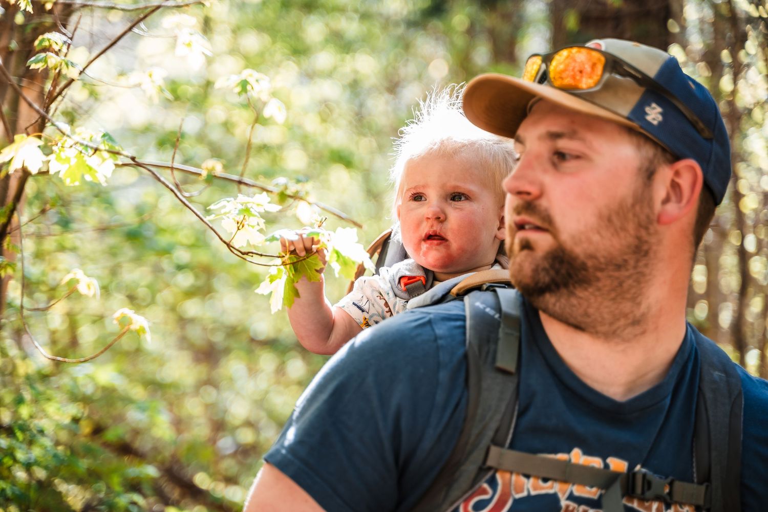 Two people explore nature together on a sunny day in the forest, with one carrying the other on their back.