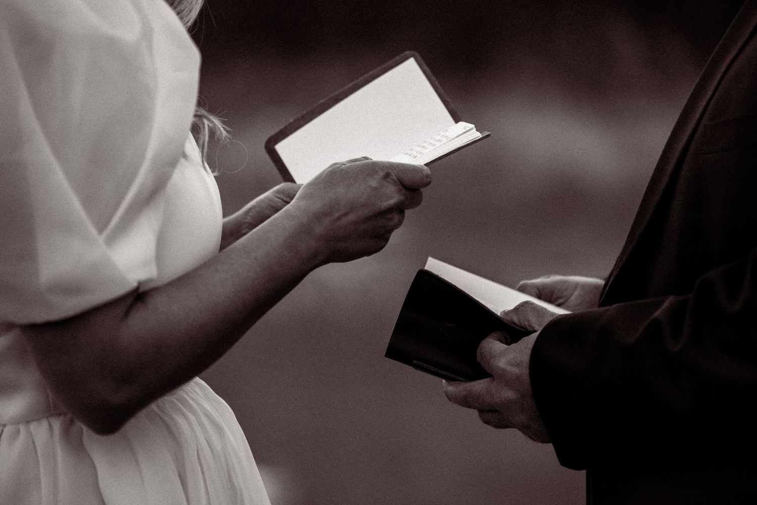 Close-up shots of hands exchanging written vows during an intimate wedding ceremony.
