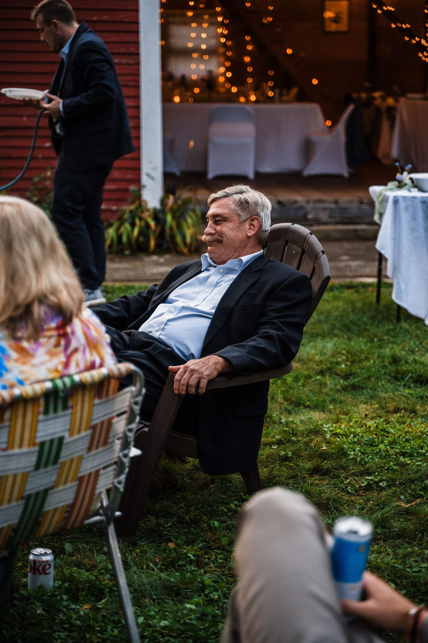 A guest relaxes in an outdoor chair during an evening wedding reception.