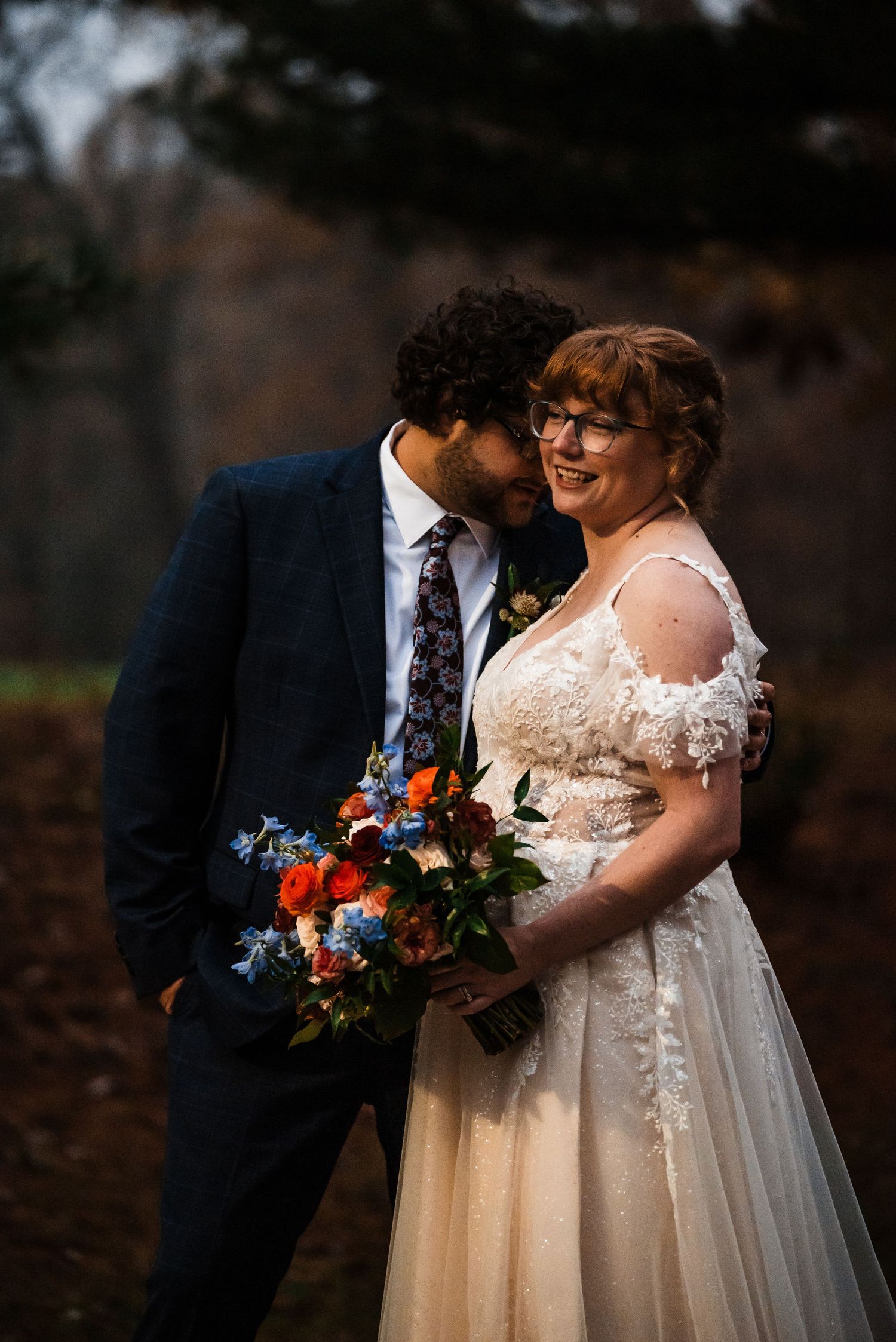 A romantic autumn wedding portrait with a beautiful bouquet of blue and orange flowers.