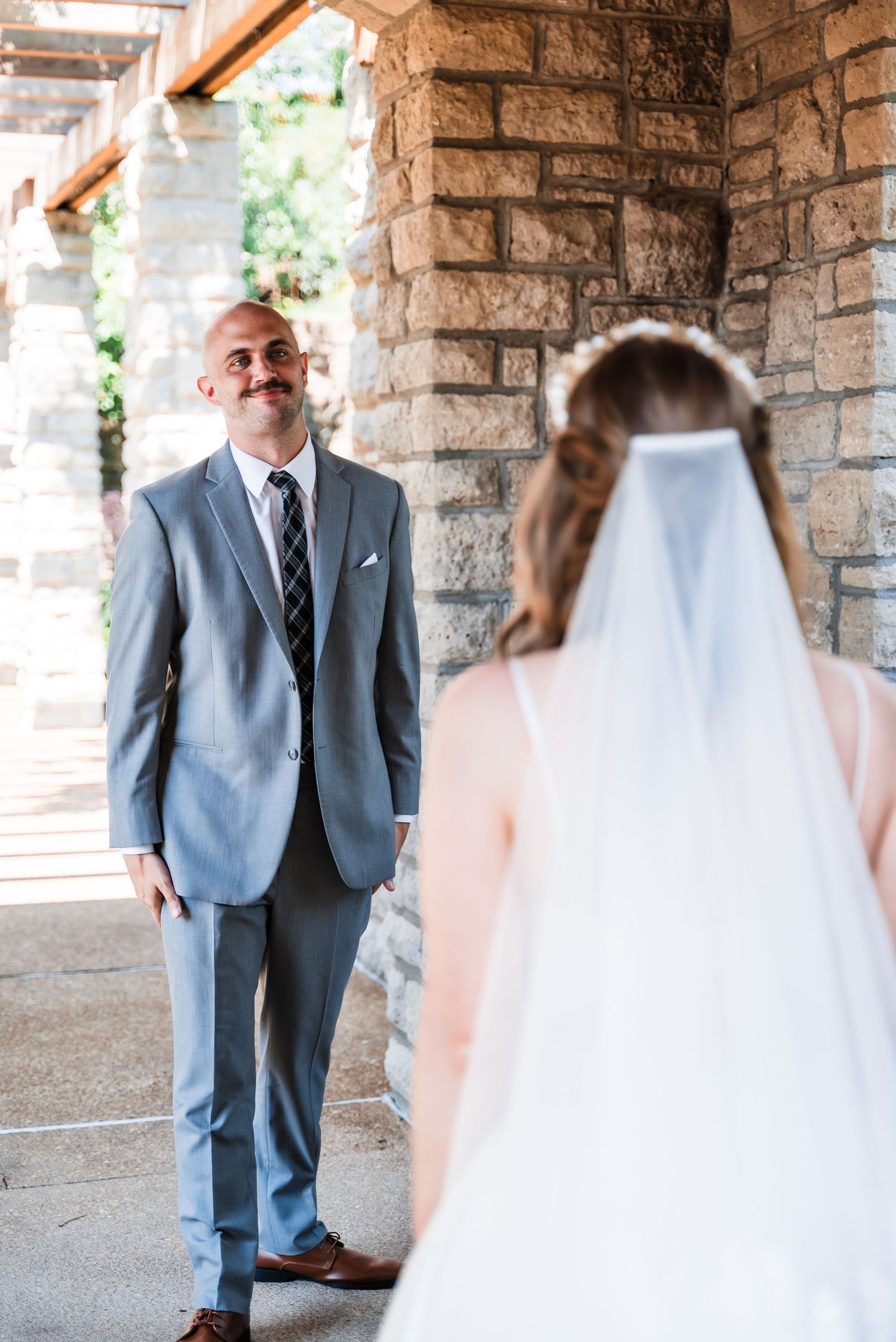 A couple shares a special first look moment in a stone archway before their wedding ceremony.