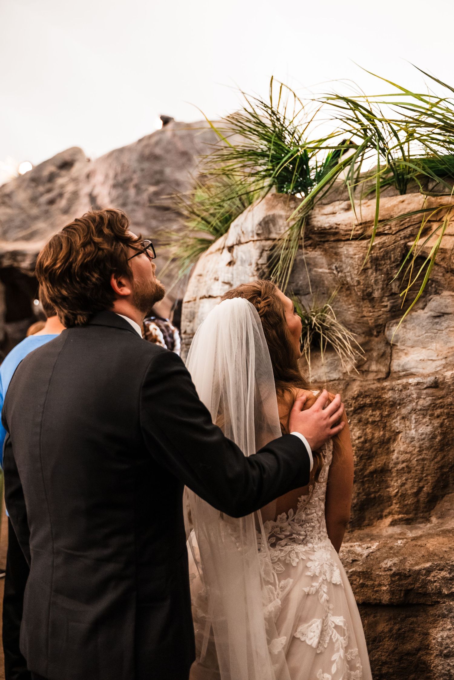 Couple admires rocky landscape during outdoor wedding photoshoot.