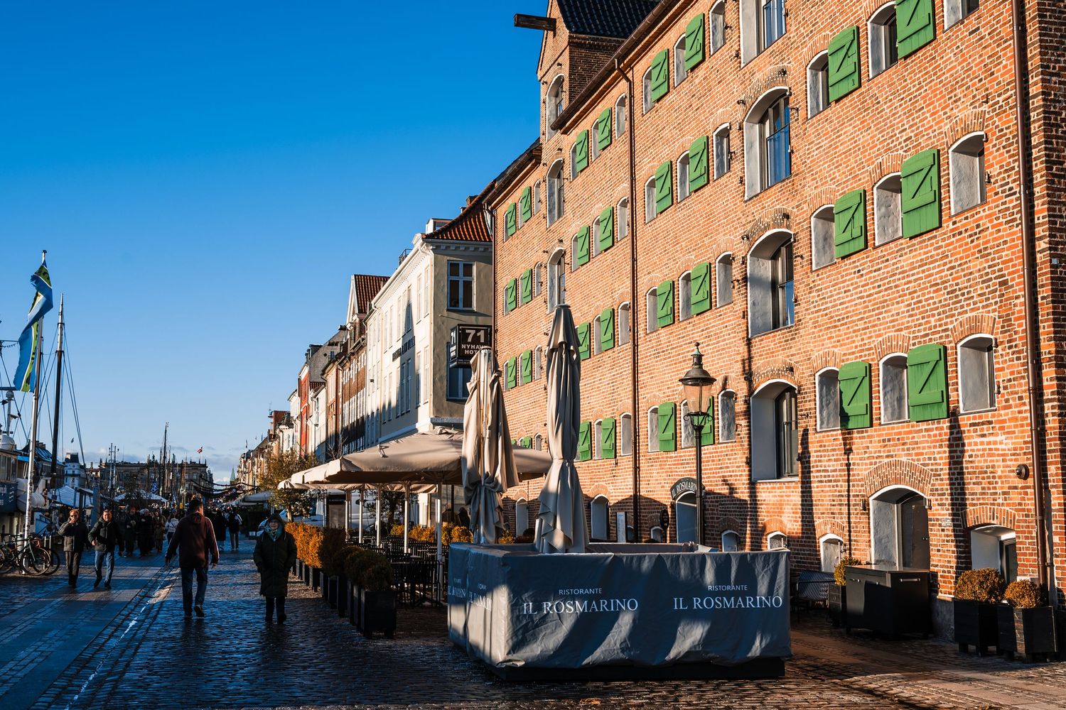 Panoramic view of historic brick buildings with green shutters along a waterfront street in Venice, Italy.