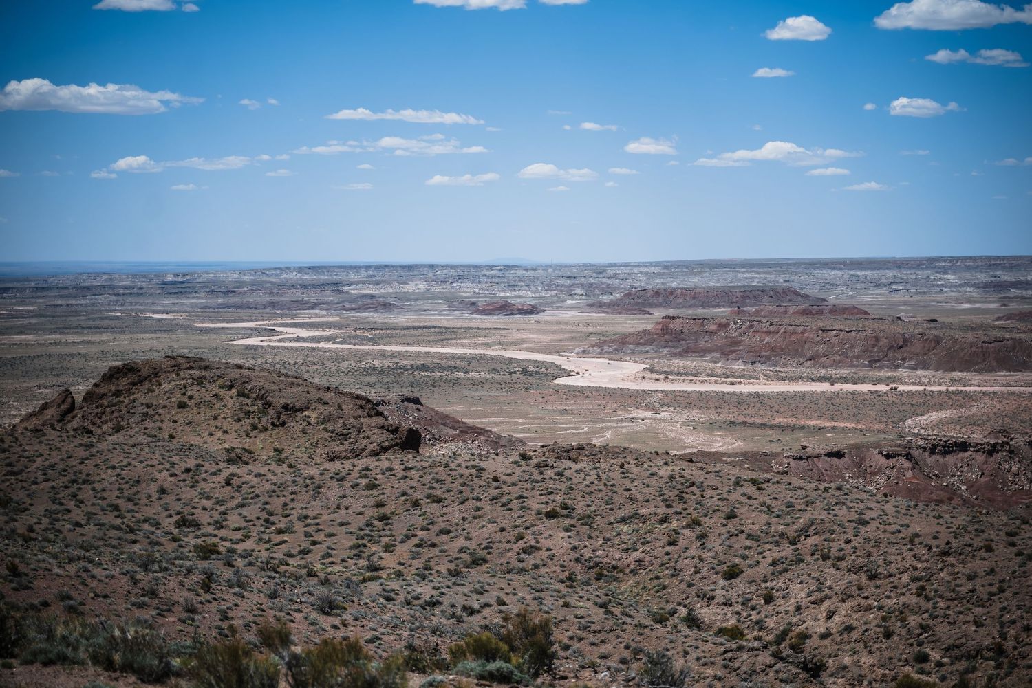 Expansive desert vista featuring layered rock formations and valleys stretching to the horizon.
