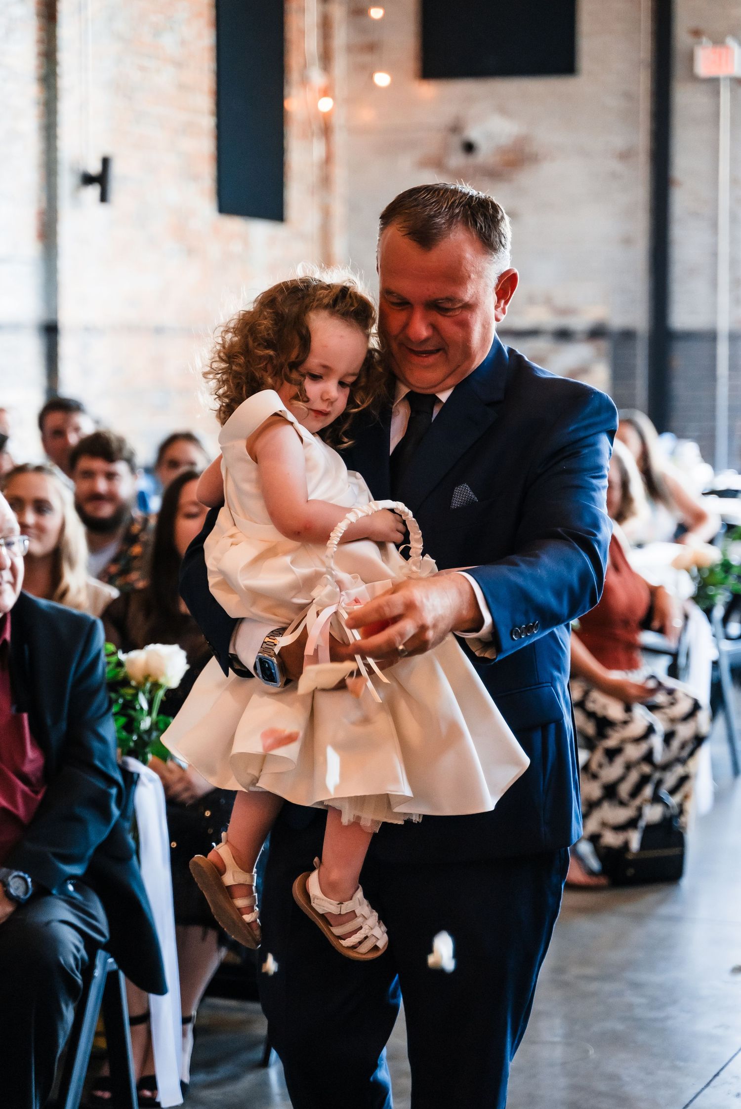 A heartwarming father-daughter dance moment at a wedding reception in an industrial venue.