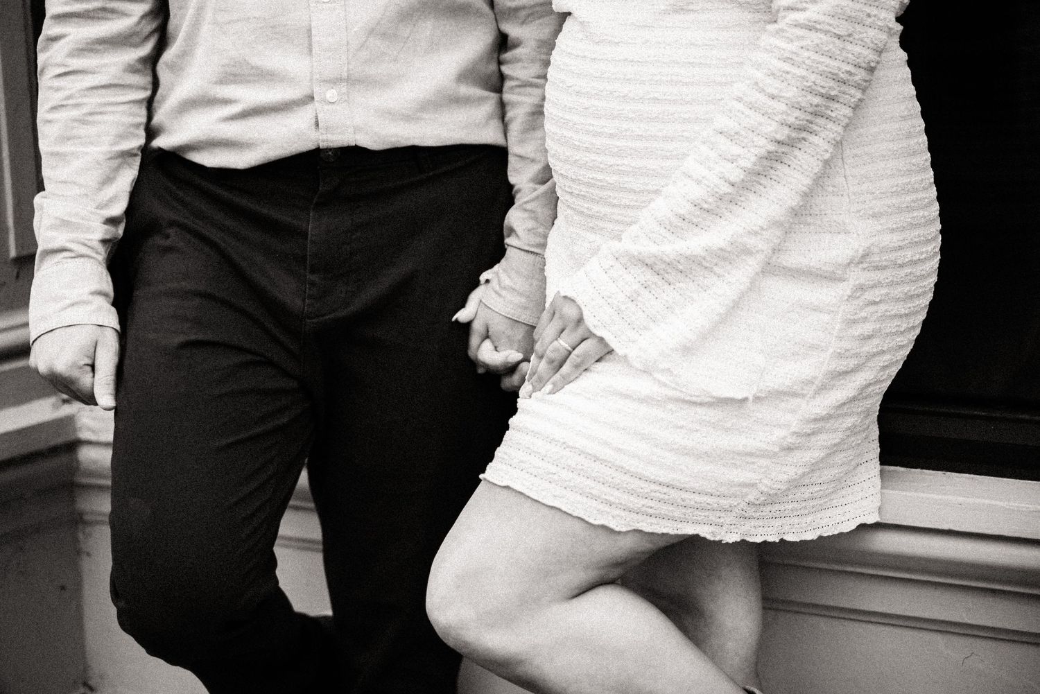 Black and white closeup of two people's lower bodies in formal attire standing together.