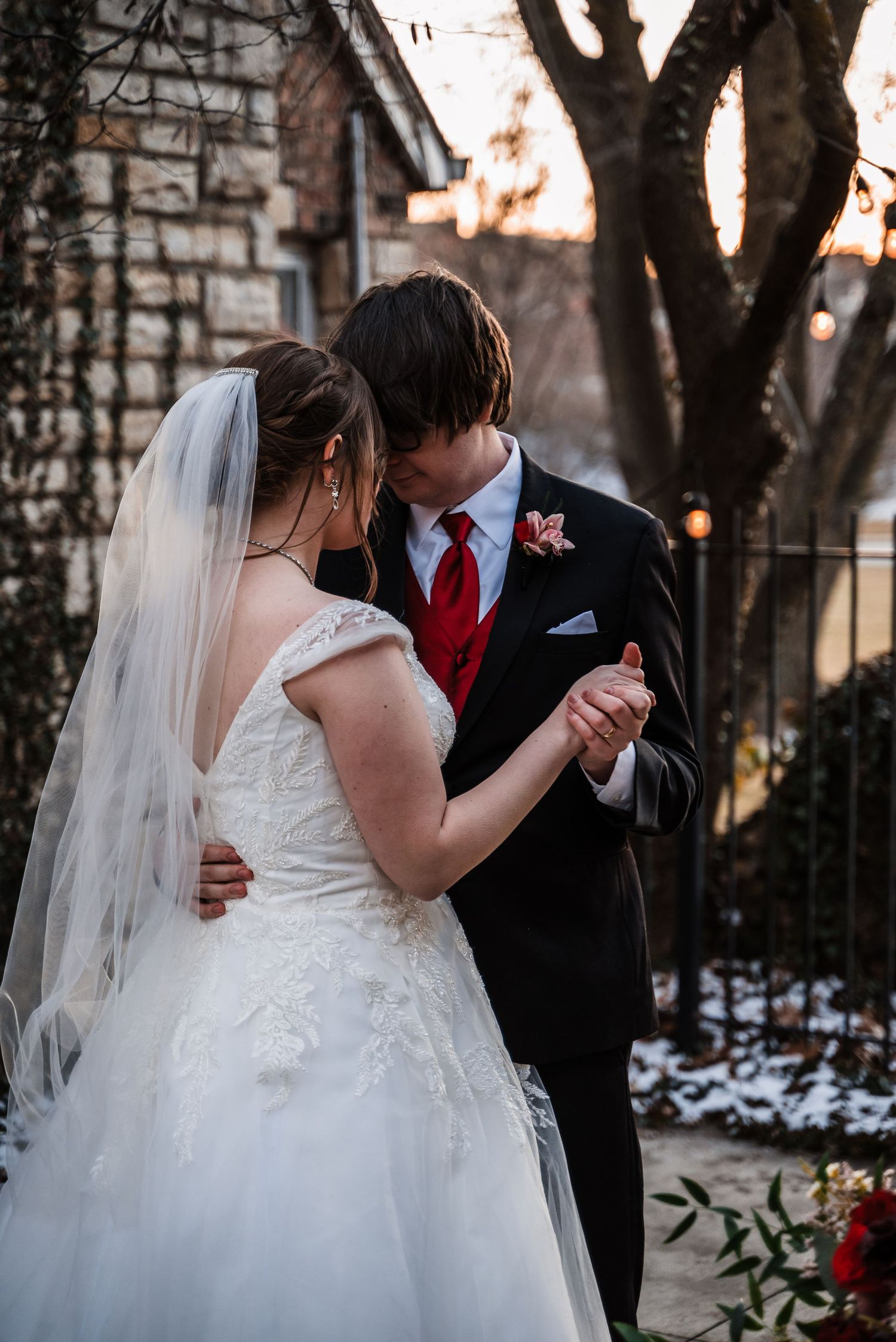 A couple shares their first dance outside a stone church during their winter wedding celebration.