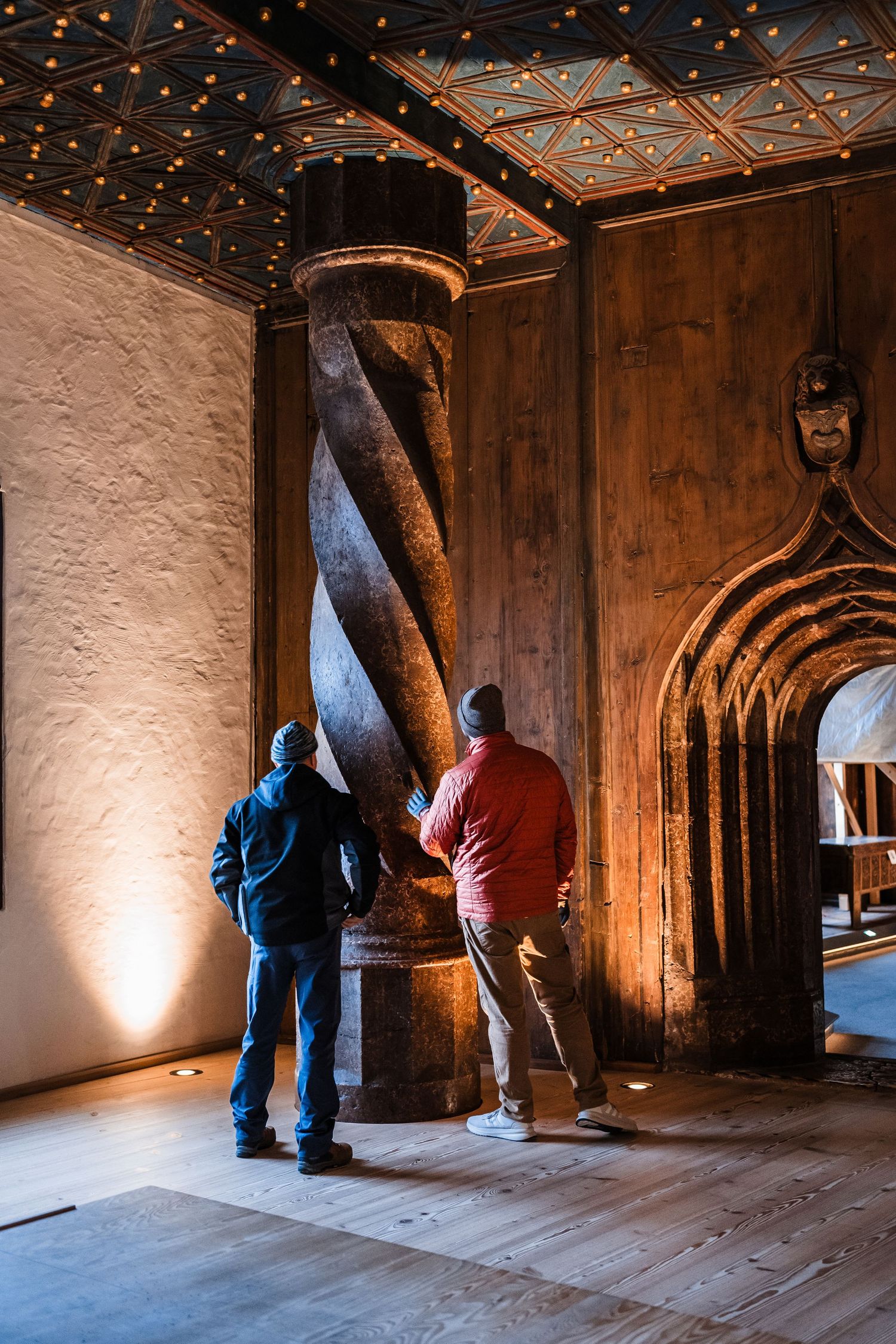 Visitors exploring a dimly lit historic wooden interior space with arched architectural details.